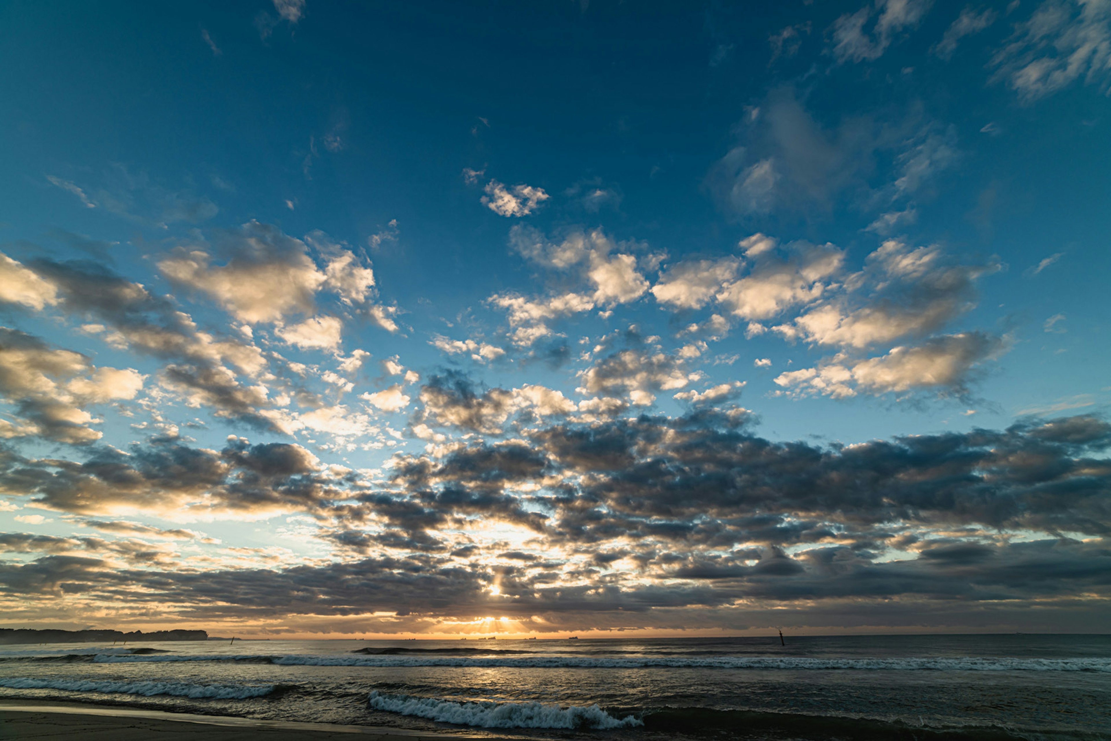 Langit senja pantai dengan awan tersebar dan nuansa biru