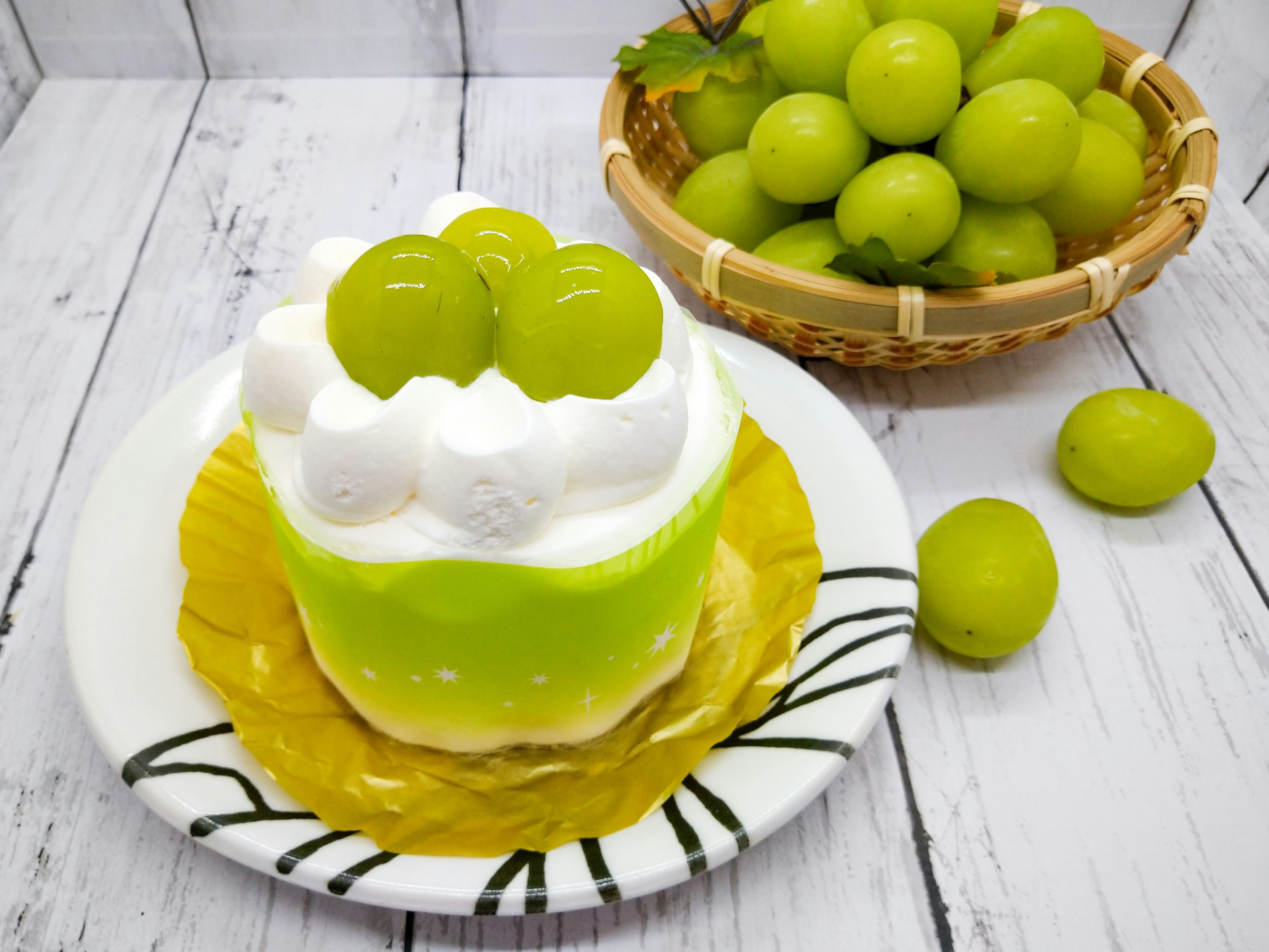 Green cake topped with white cream and green grapes