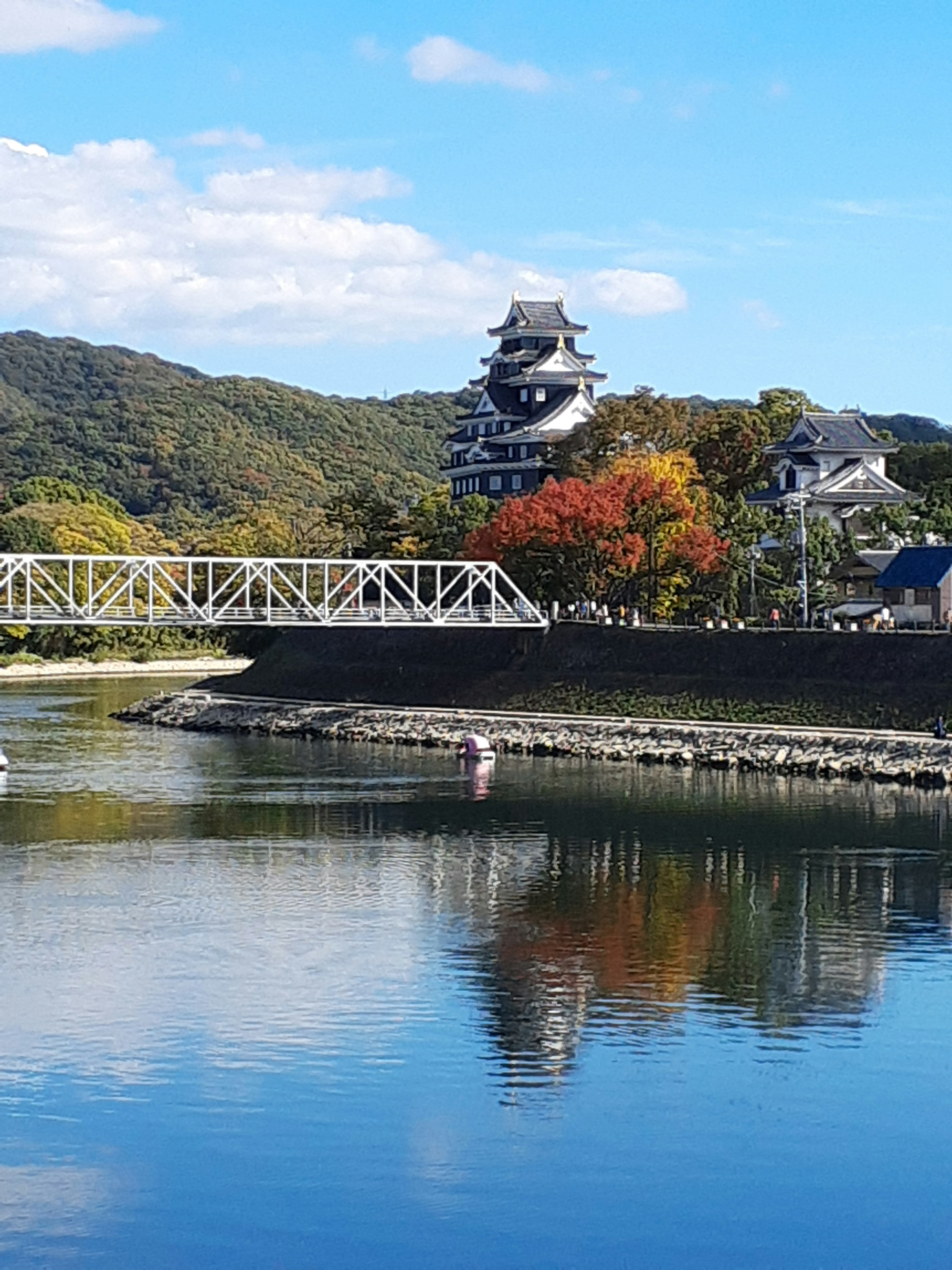 Vista escénica del río con un castillo y reflejos de follaje otoñal