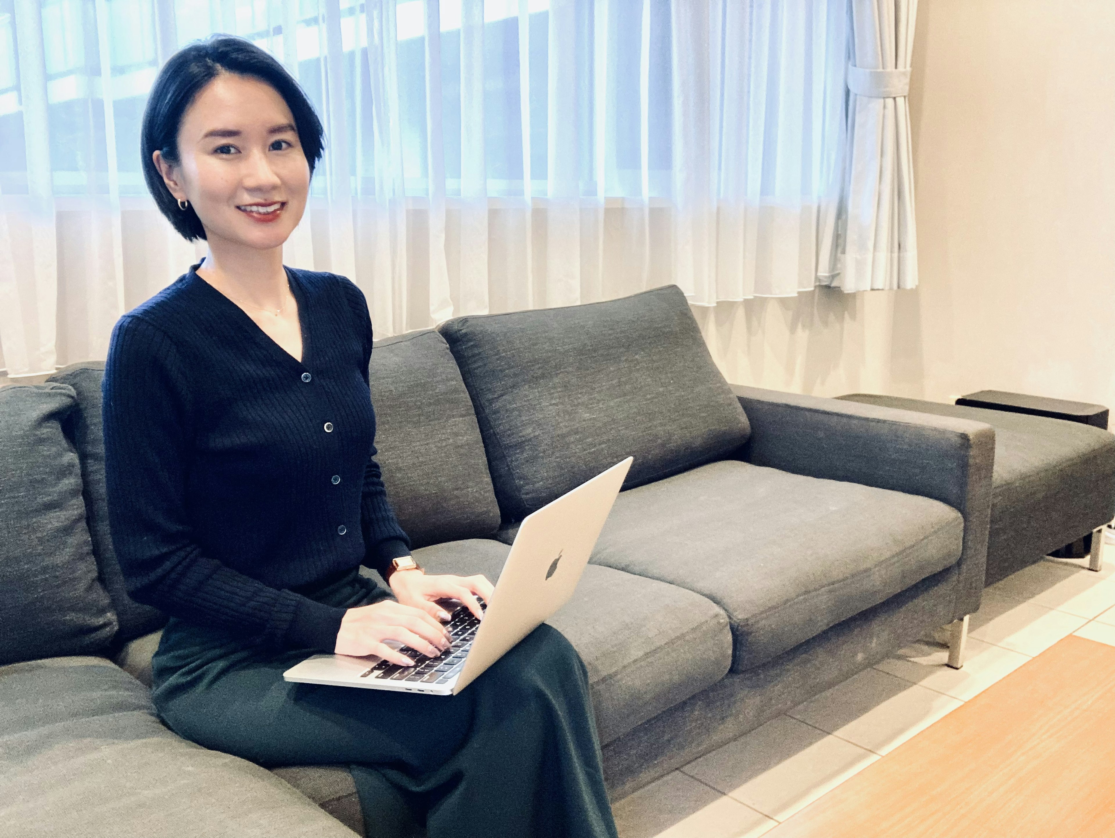 A woman sitting on a sofa using a laptop