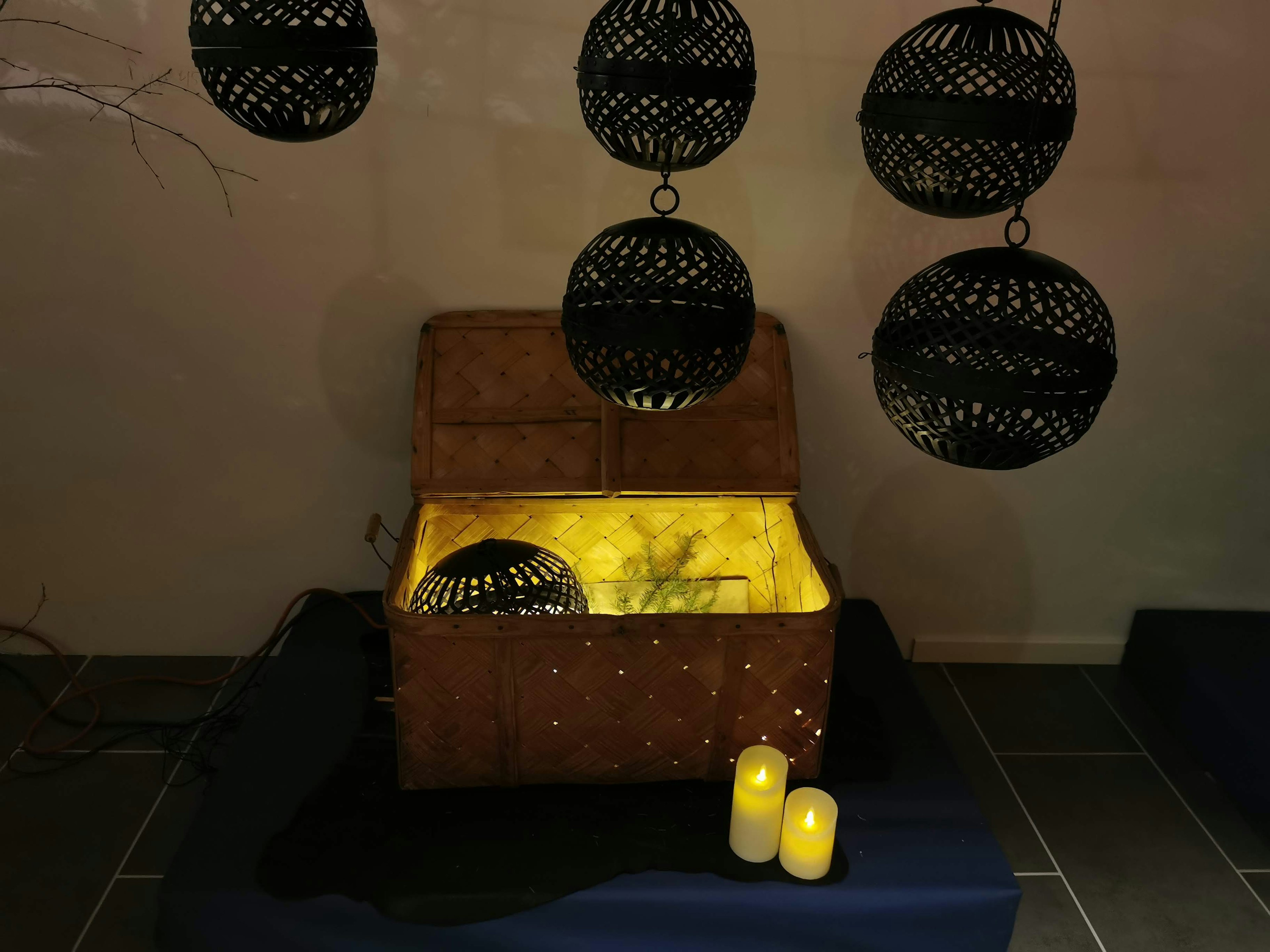 A wooden treasure chest glowing with yellow light surrounded by hanging black decorative spheres