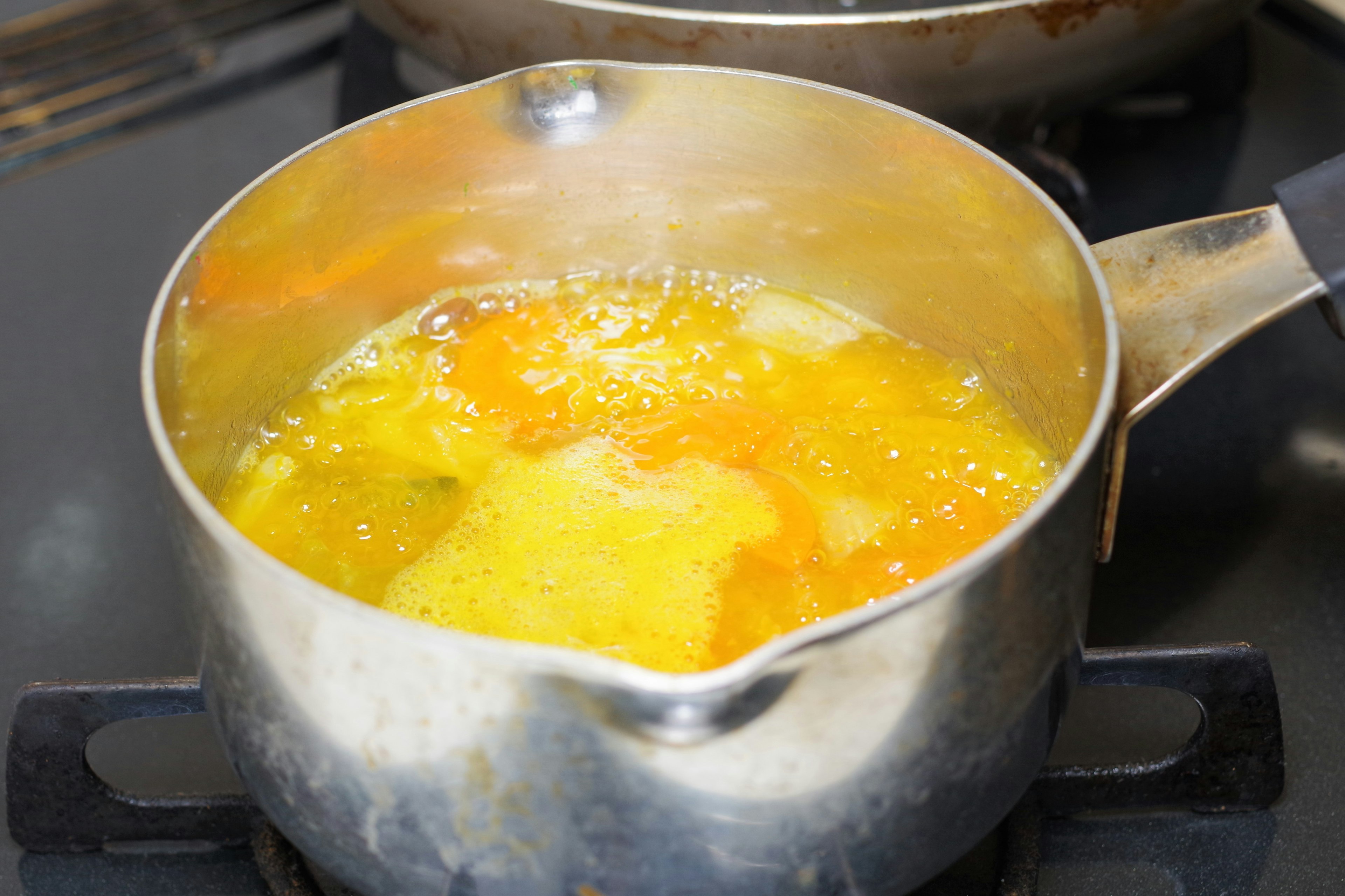 A pot boiling with orange vegetables and broth