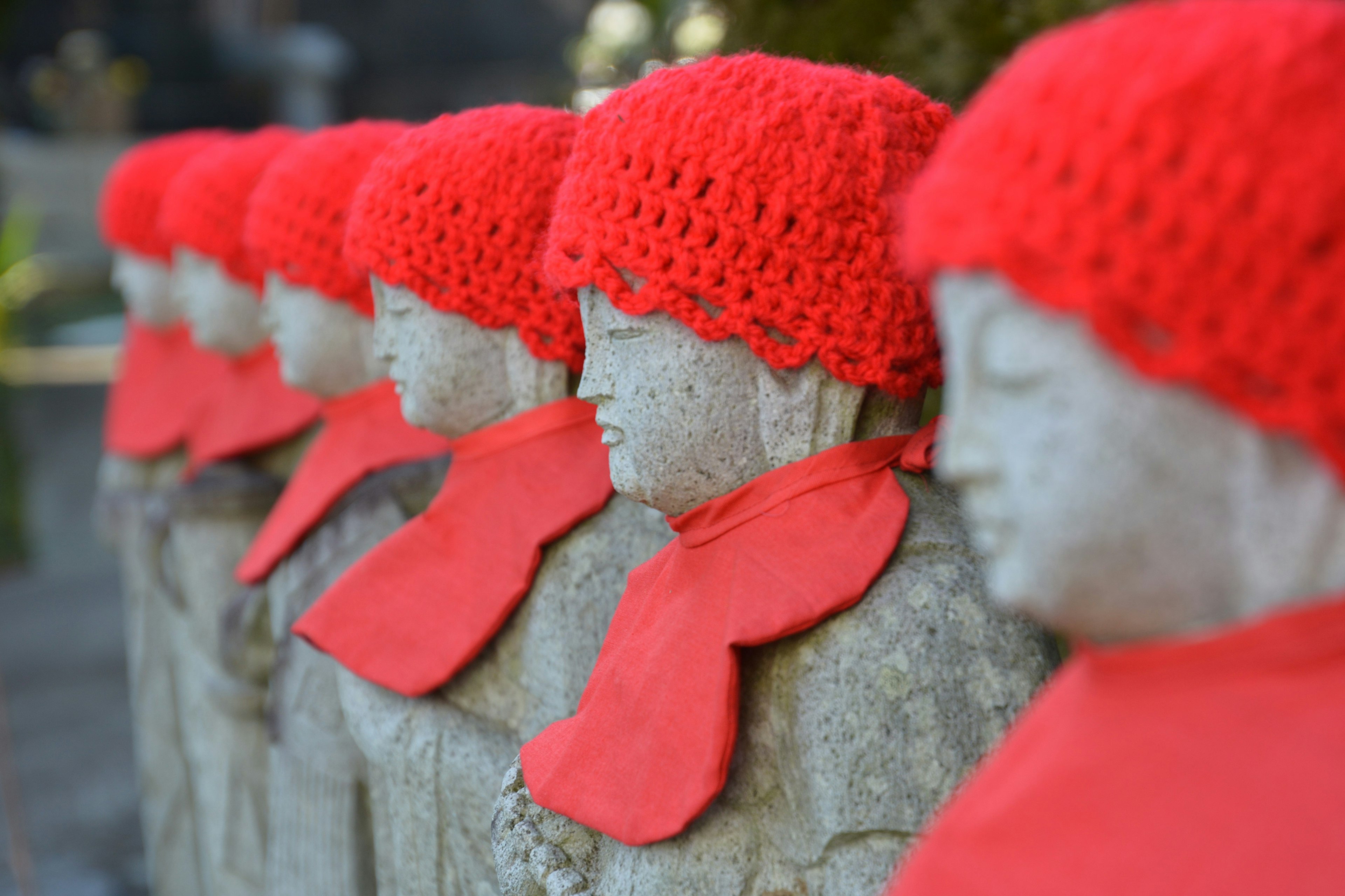 Rang de statues en pierre portant des chapeaux et des écharpes rouges