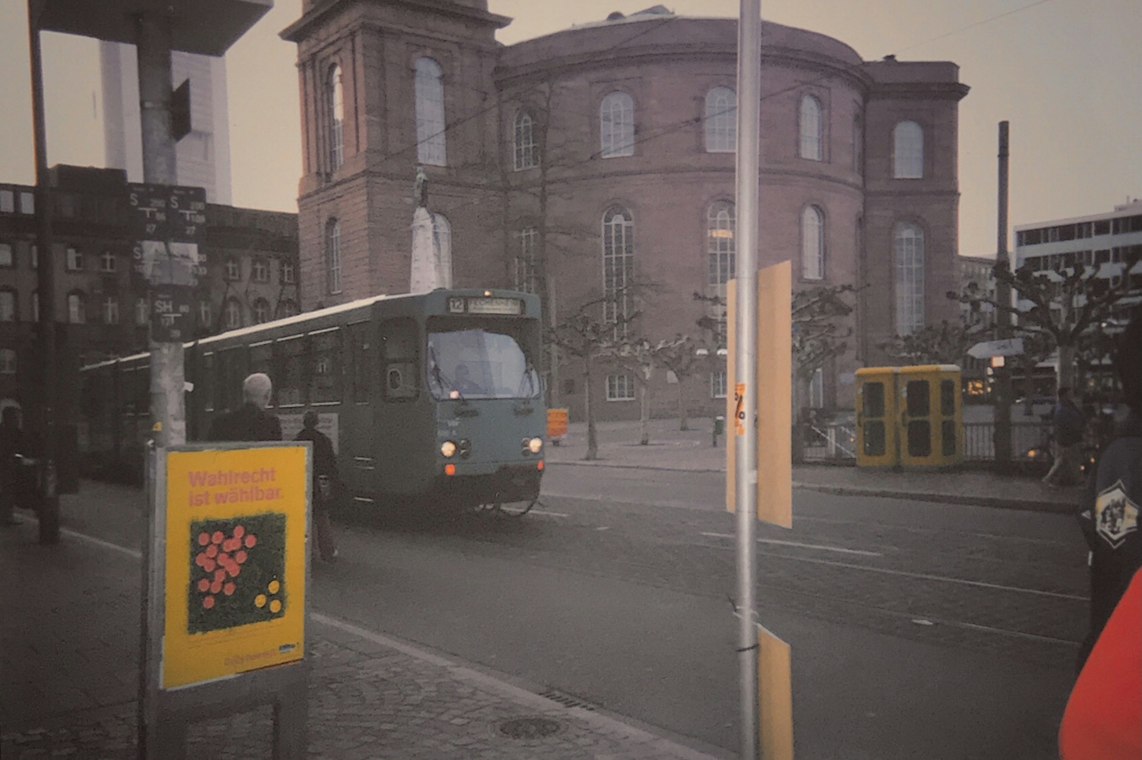 Bus vert tournant à un coin de rue avec un bâtiment historique en arrière-plan