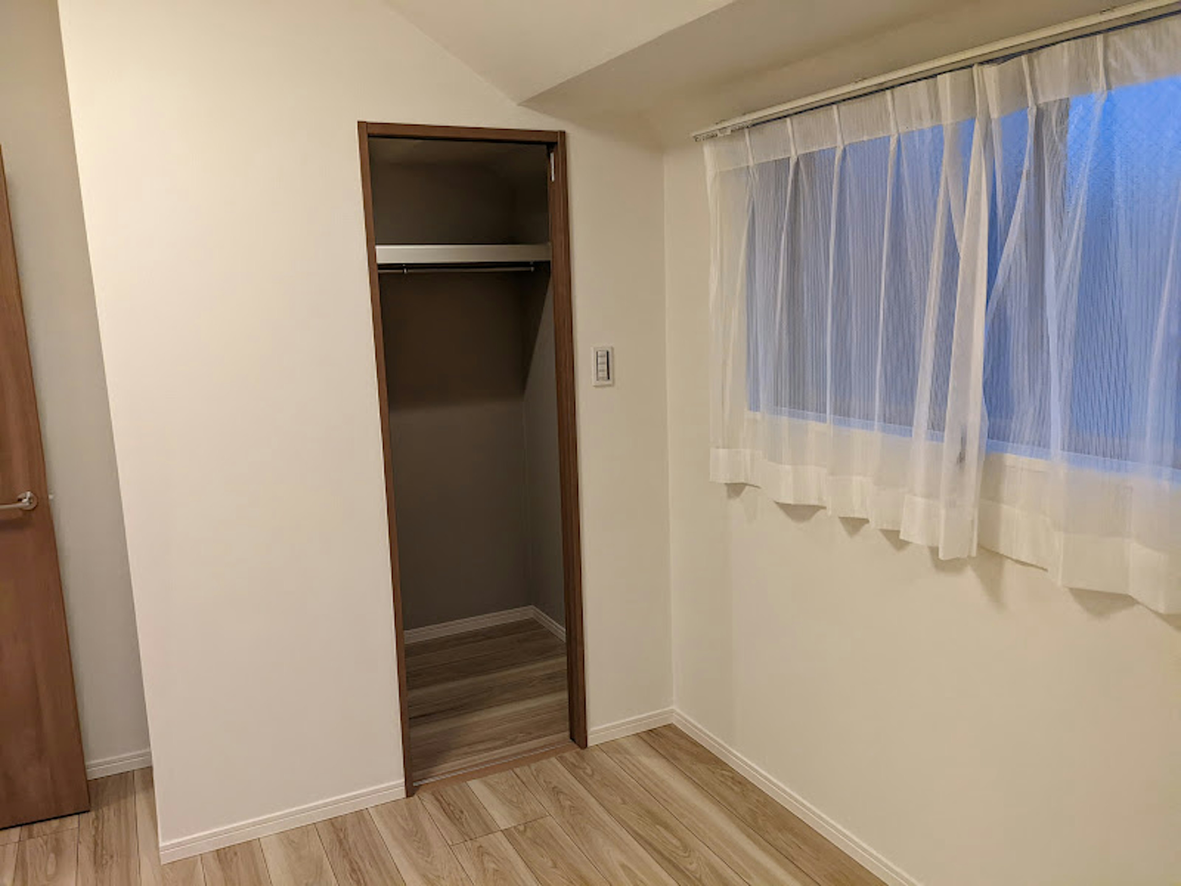 A bright room featuring a window and a closet with a simple design