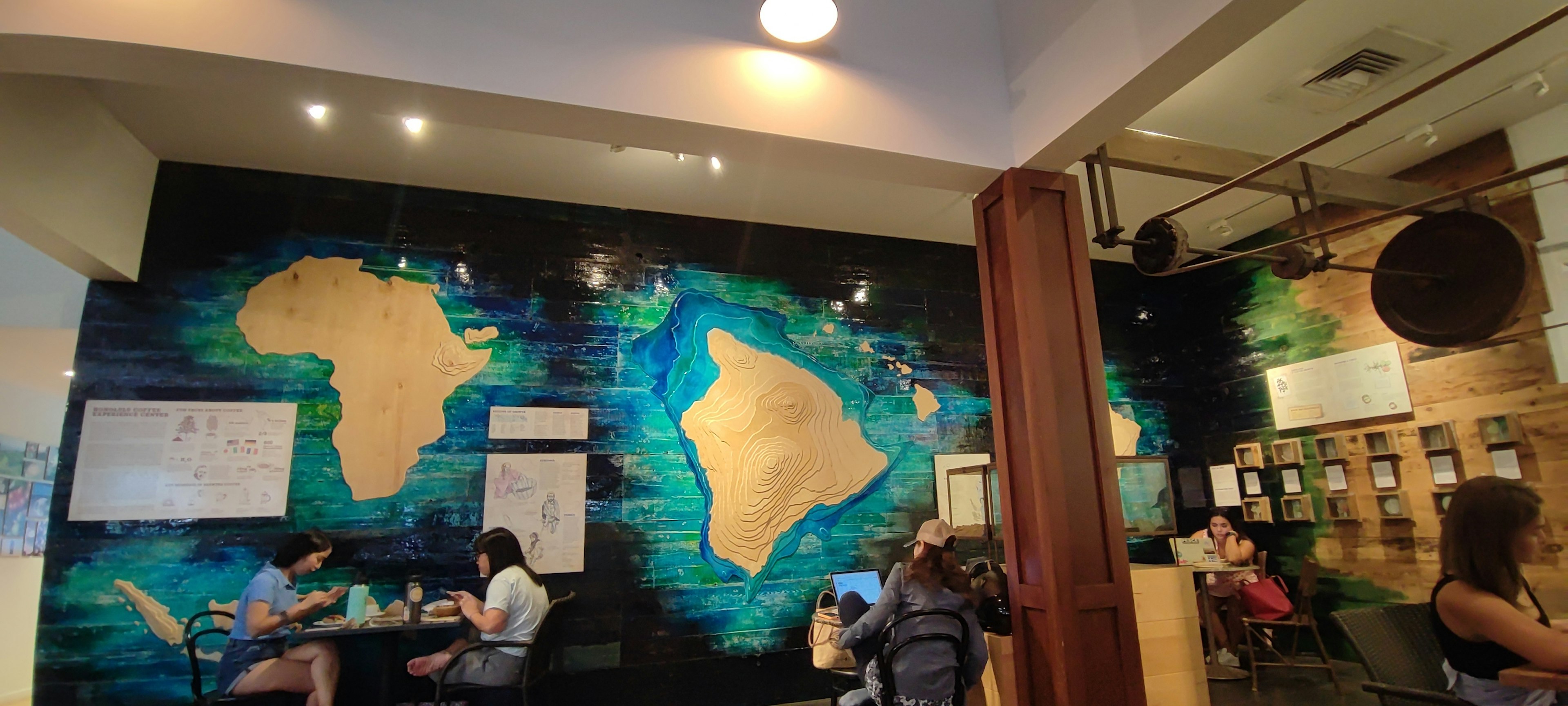 Interior of a cafe featuring a mural of Africa and Hawaii maps