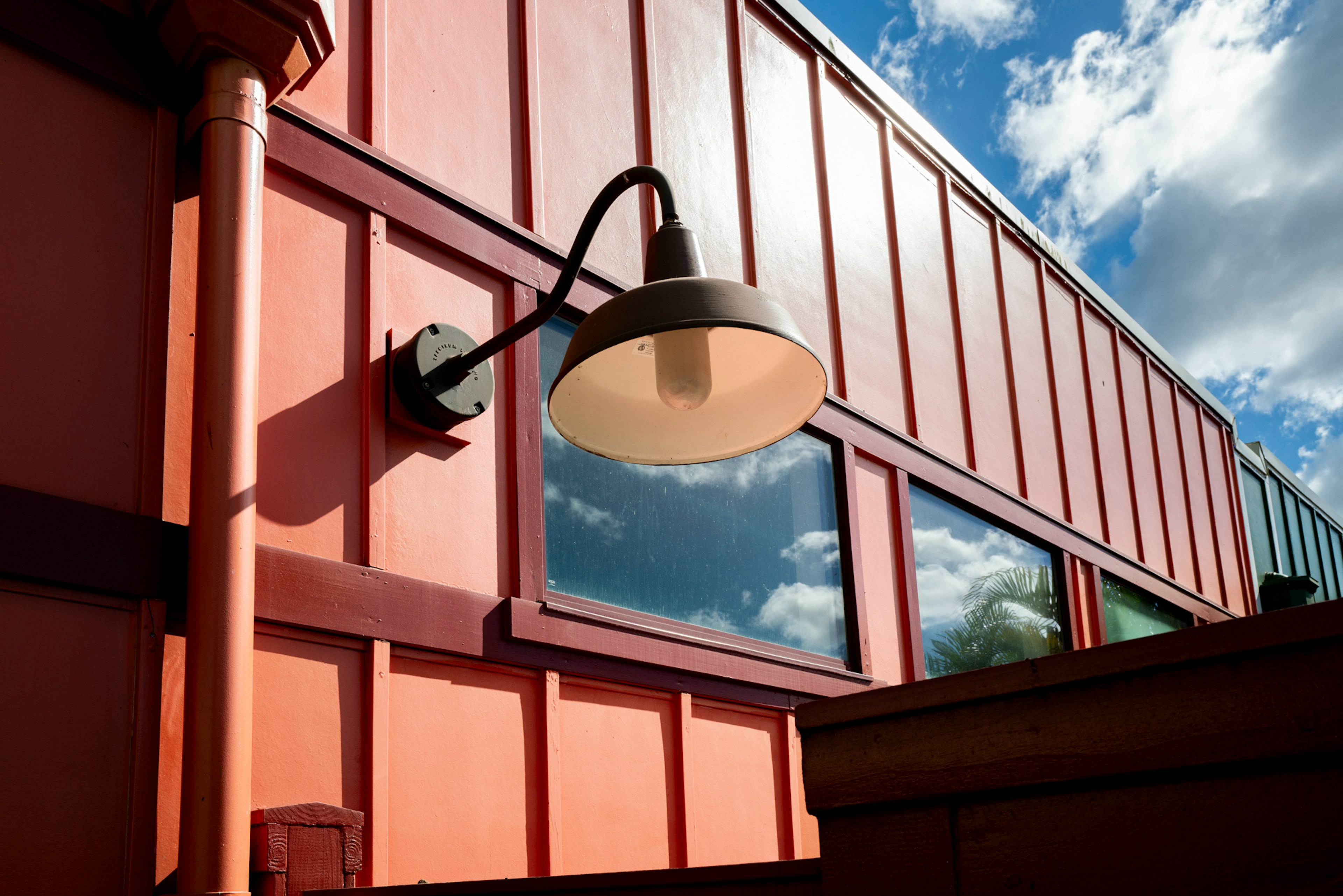 Wall-mounted light fixture on a red building with blue sky