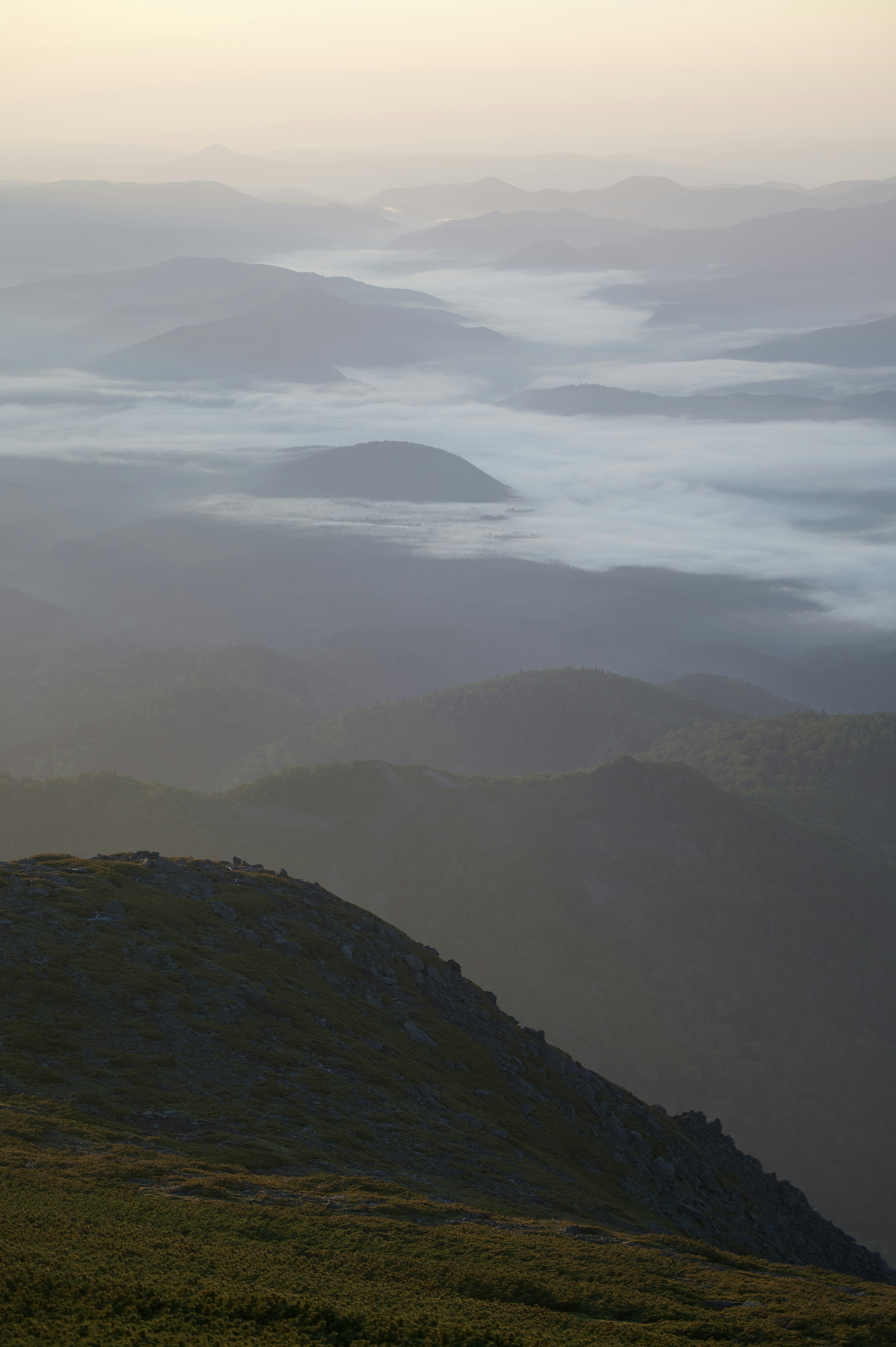 Paesaggio montano coperto di nebbia con colline lontane