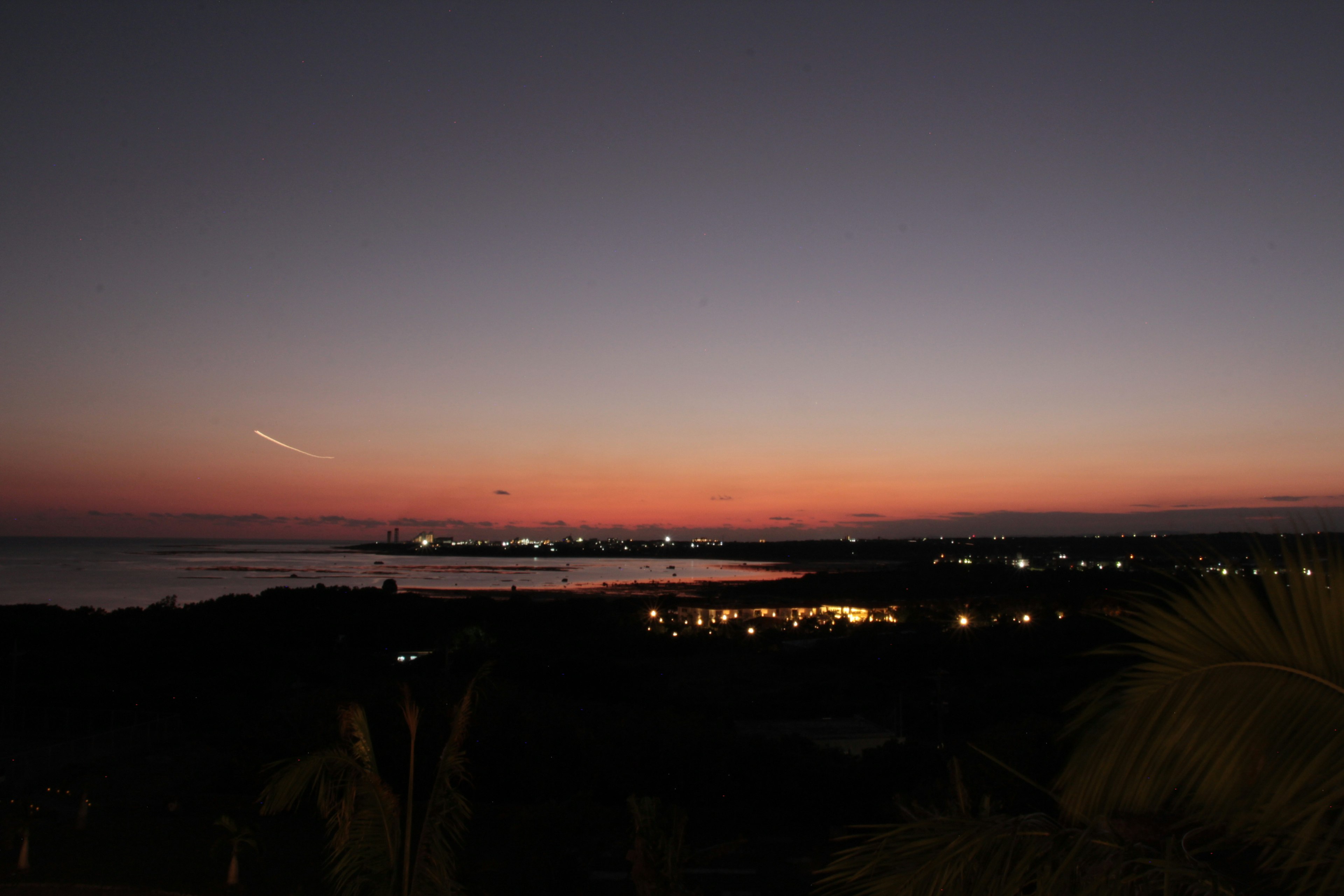 美しい夕焼けの海の風景と明かりが点在する街