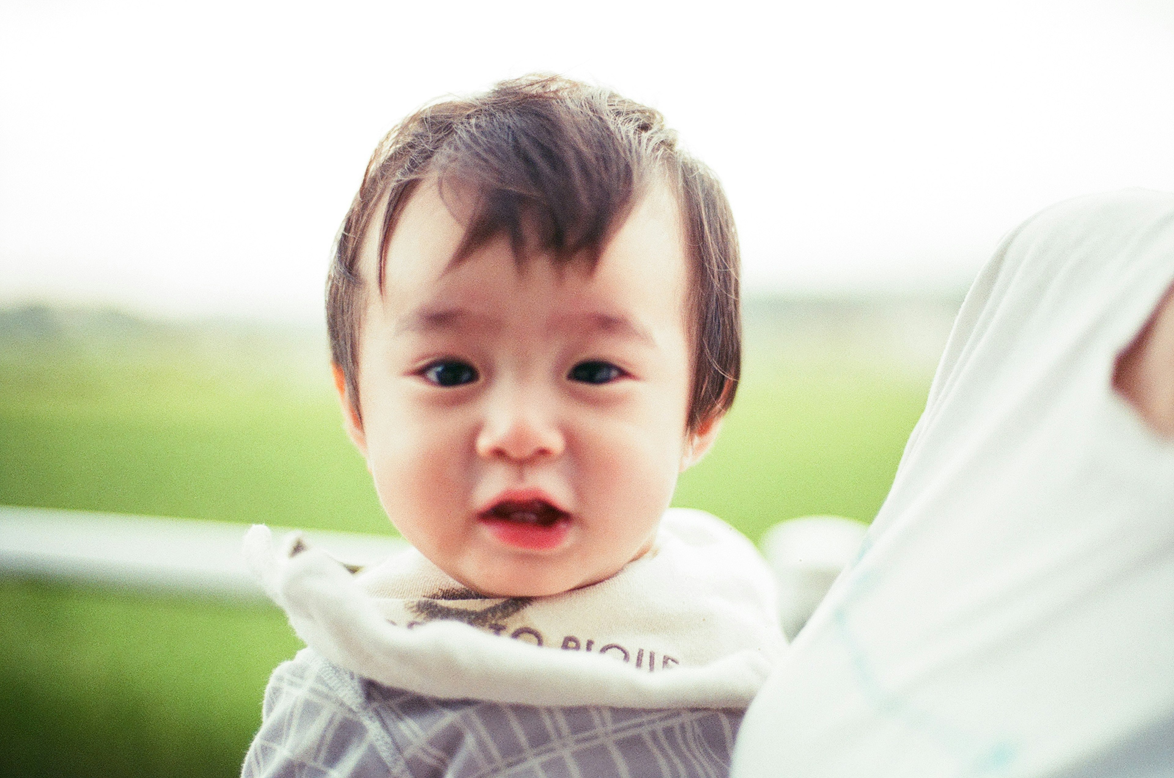 Ein lächelndes Baby schaut in die Kamera mit grünen Reisfeldern im Hintergrund