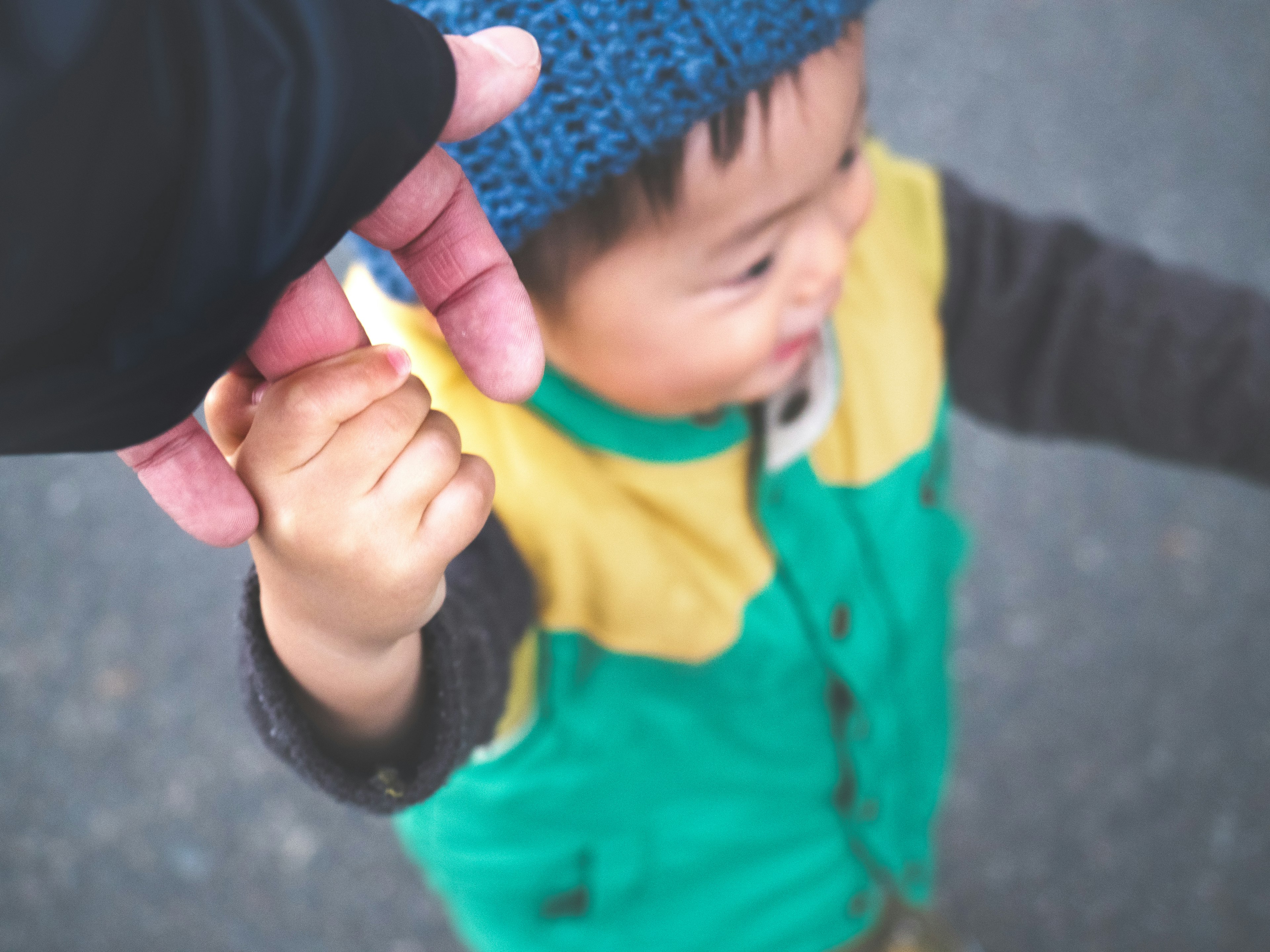 Un niño agarrando la mano de un adulto sonriendo con un atuendo colorido