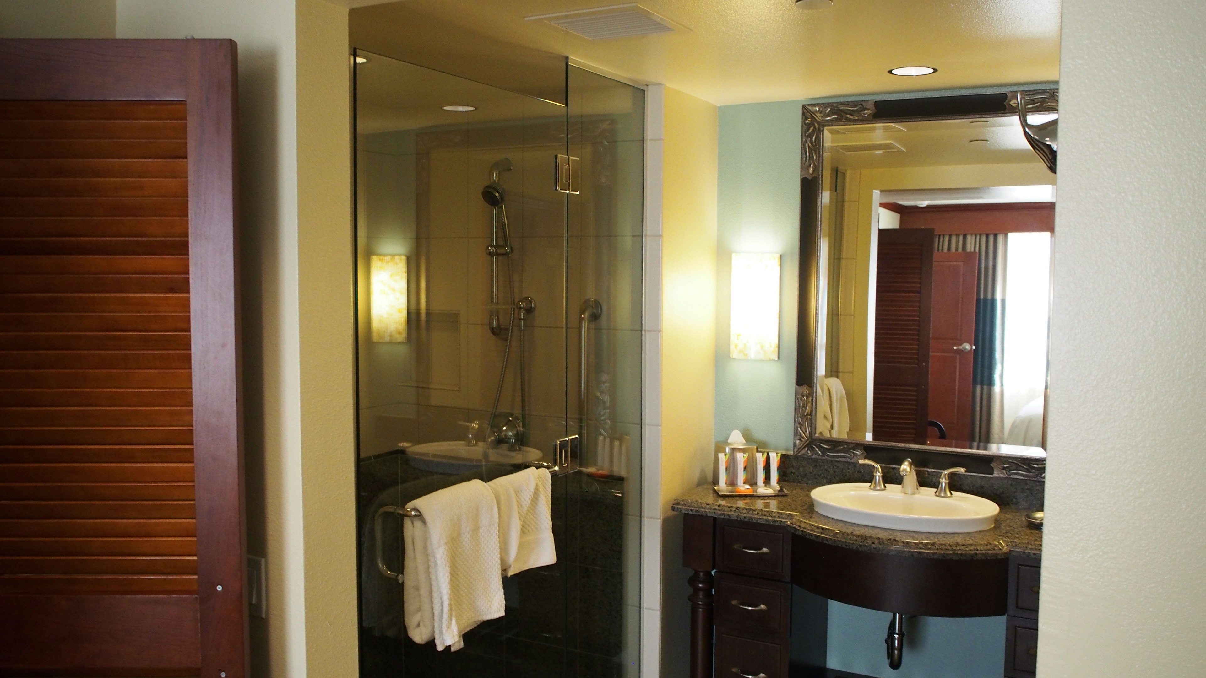 Interior de baño moderno con ducha de vidrio, lavabo, toallas y armario de madera