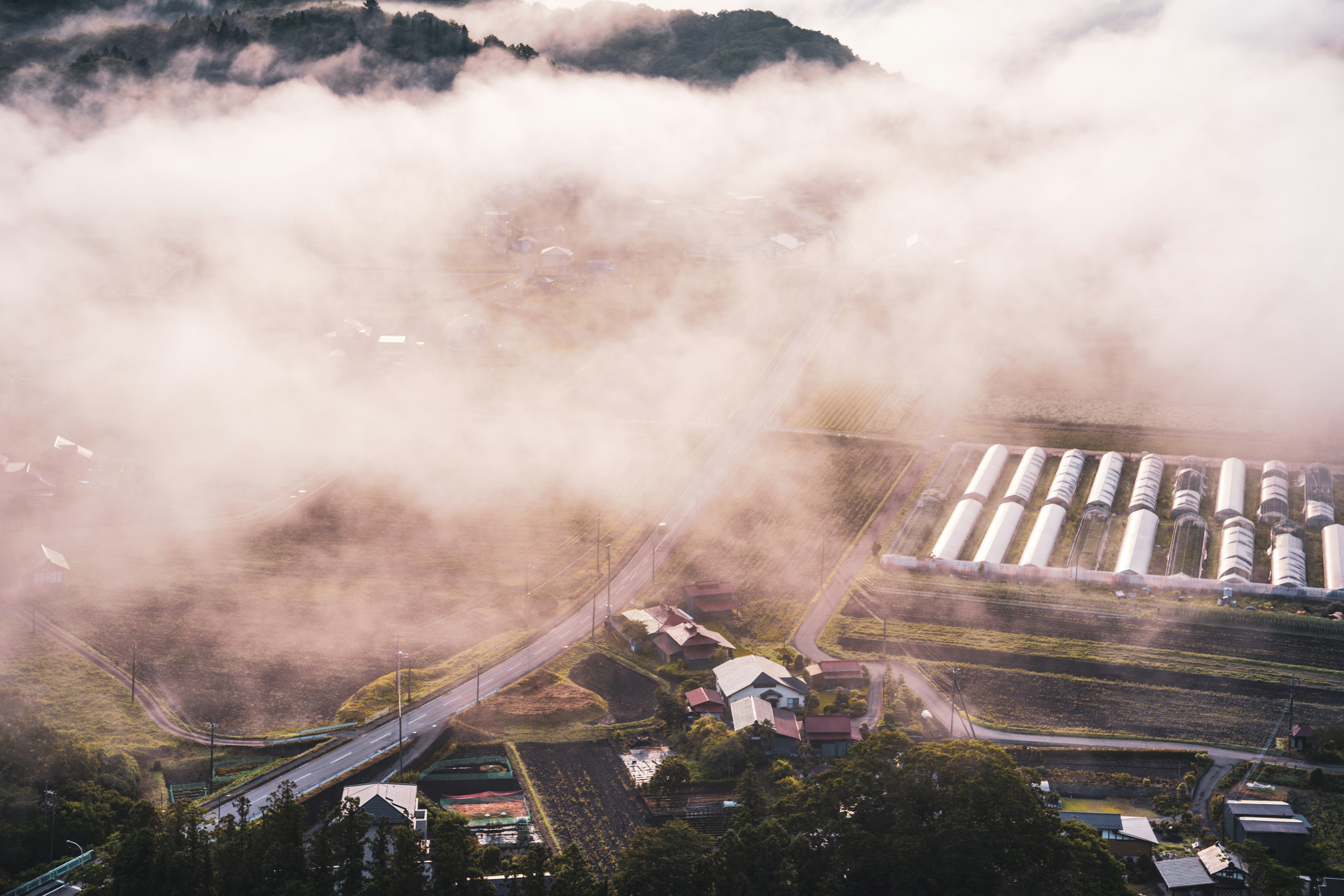 Aerial view of a fog-covered rural landscape featuring farms and winding roads