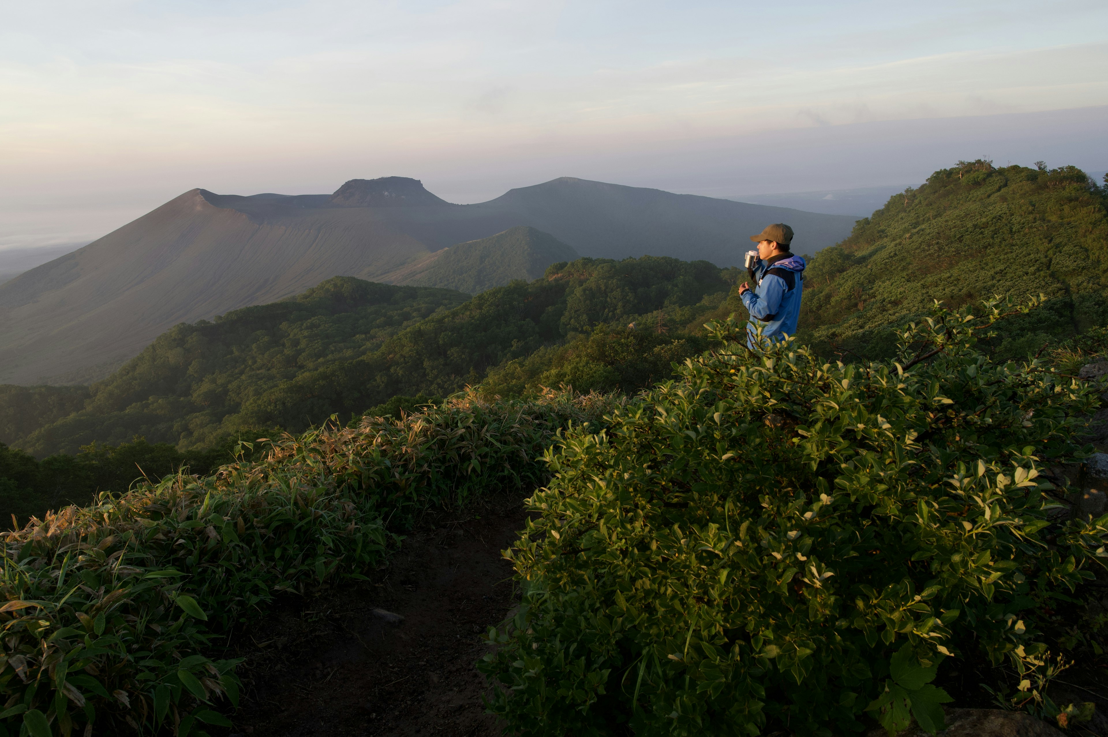 Person in blue jacket overlooking mountains at sunrise