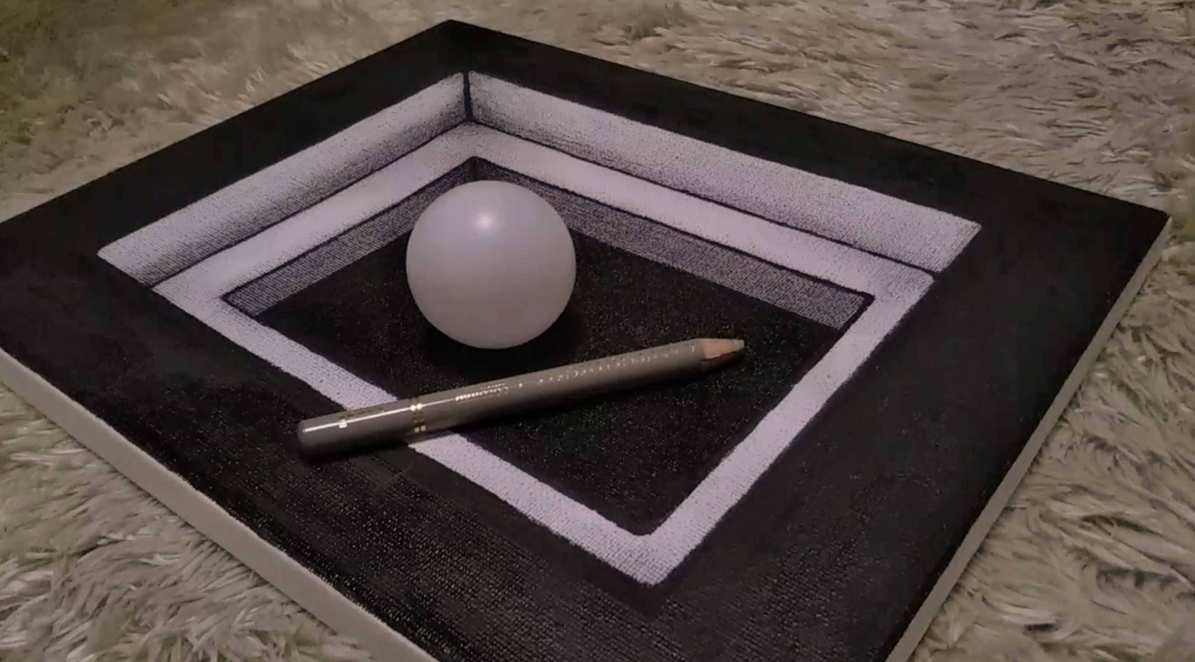 A white sphere and a silver pen placed within concentric black and white rectangular frames