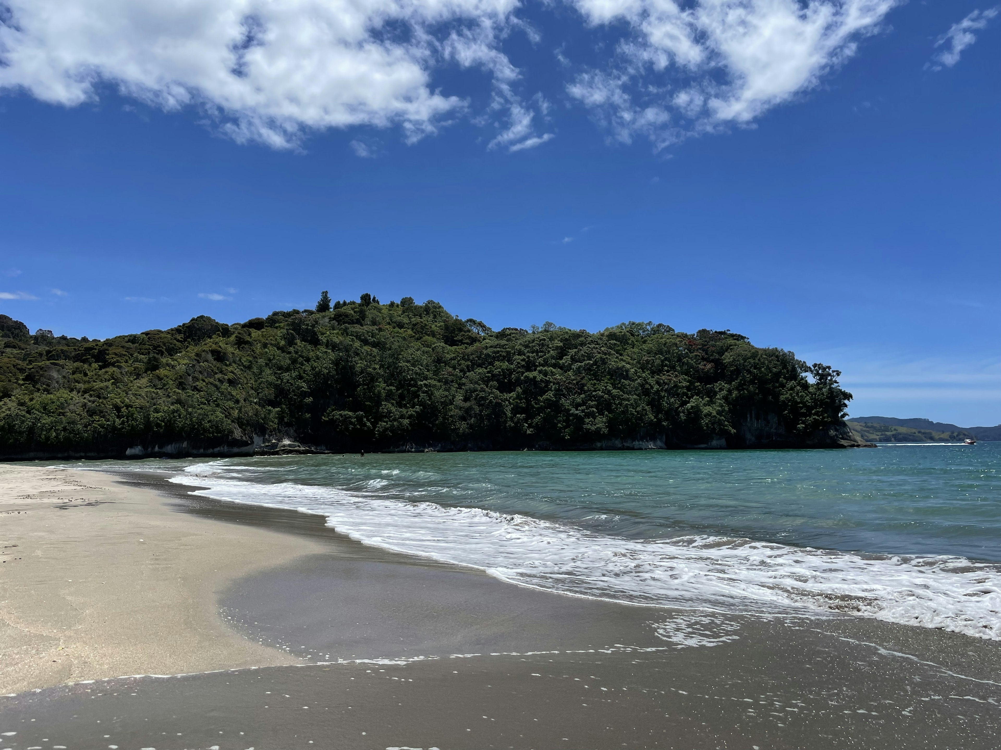 Malersicher Strandblick mit blauem Himmel und weißen Wolken sanfte Wellen am Sandstrand