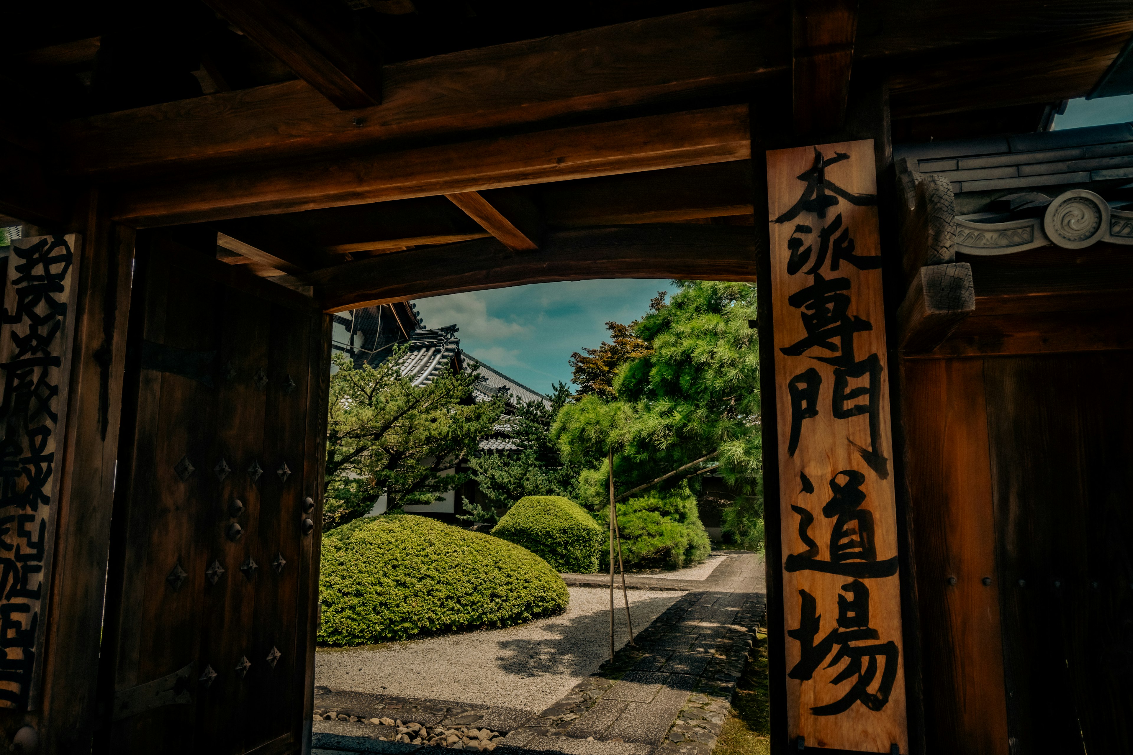 木製の門を通り抜ける美しい日本庭園の風景