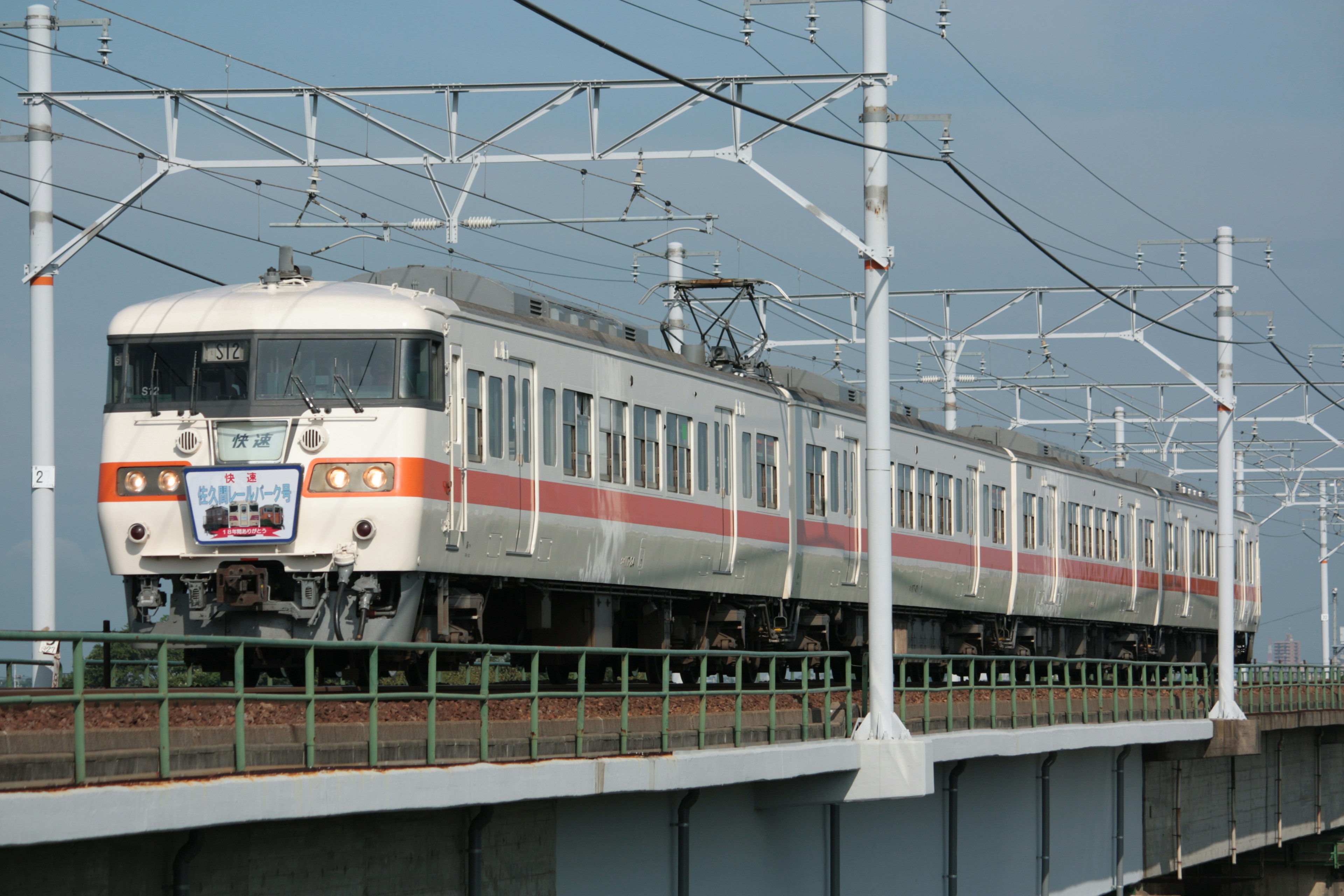 Train rayé blanc et orange circulant sur une voie surélevée