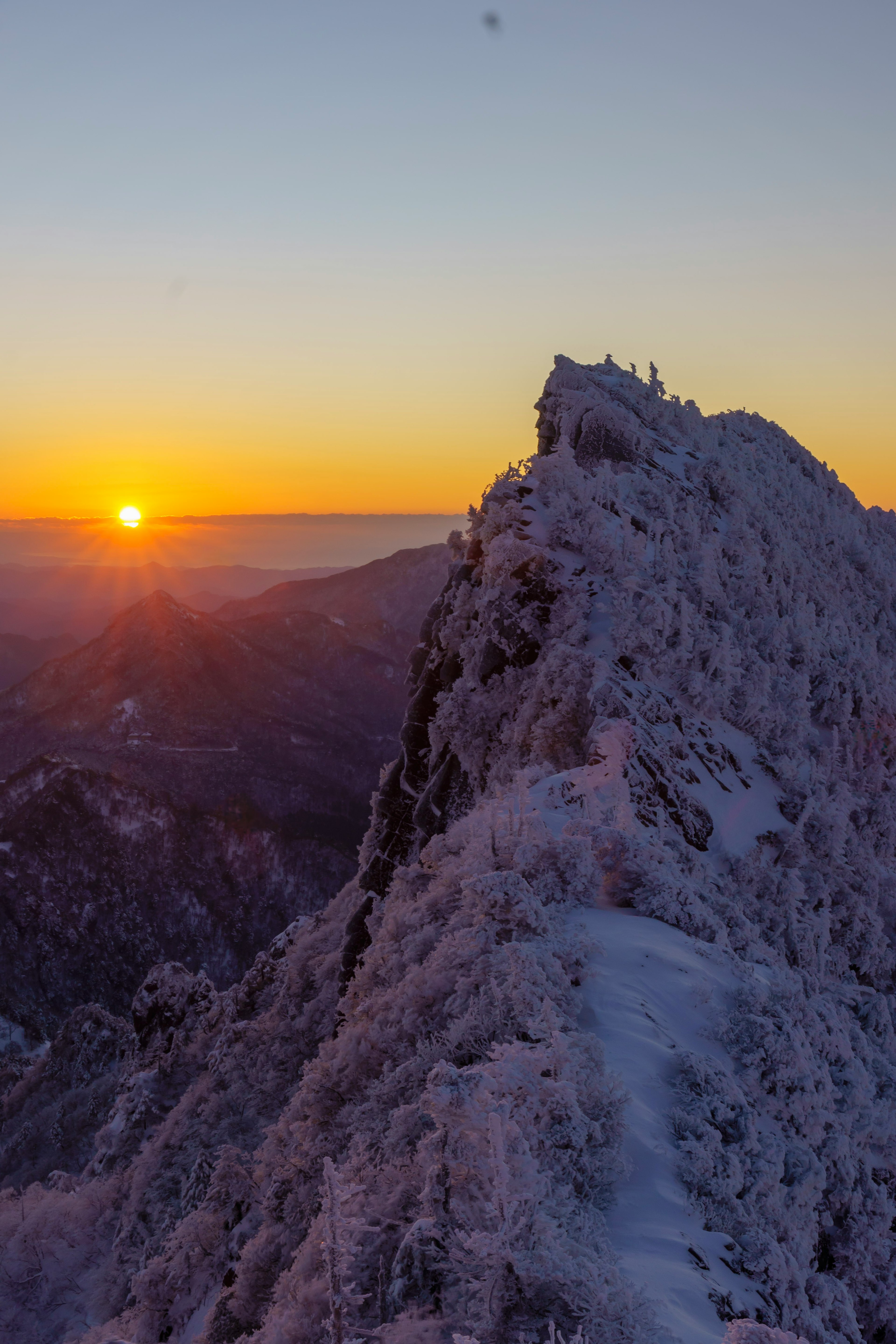 Cima de montaña cubierta de nieve con un amanecer de fondo