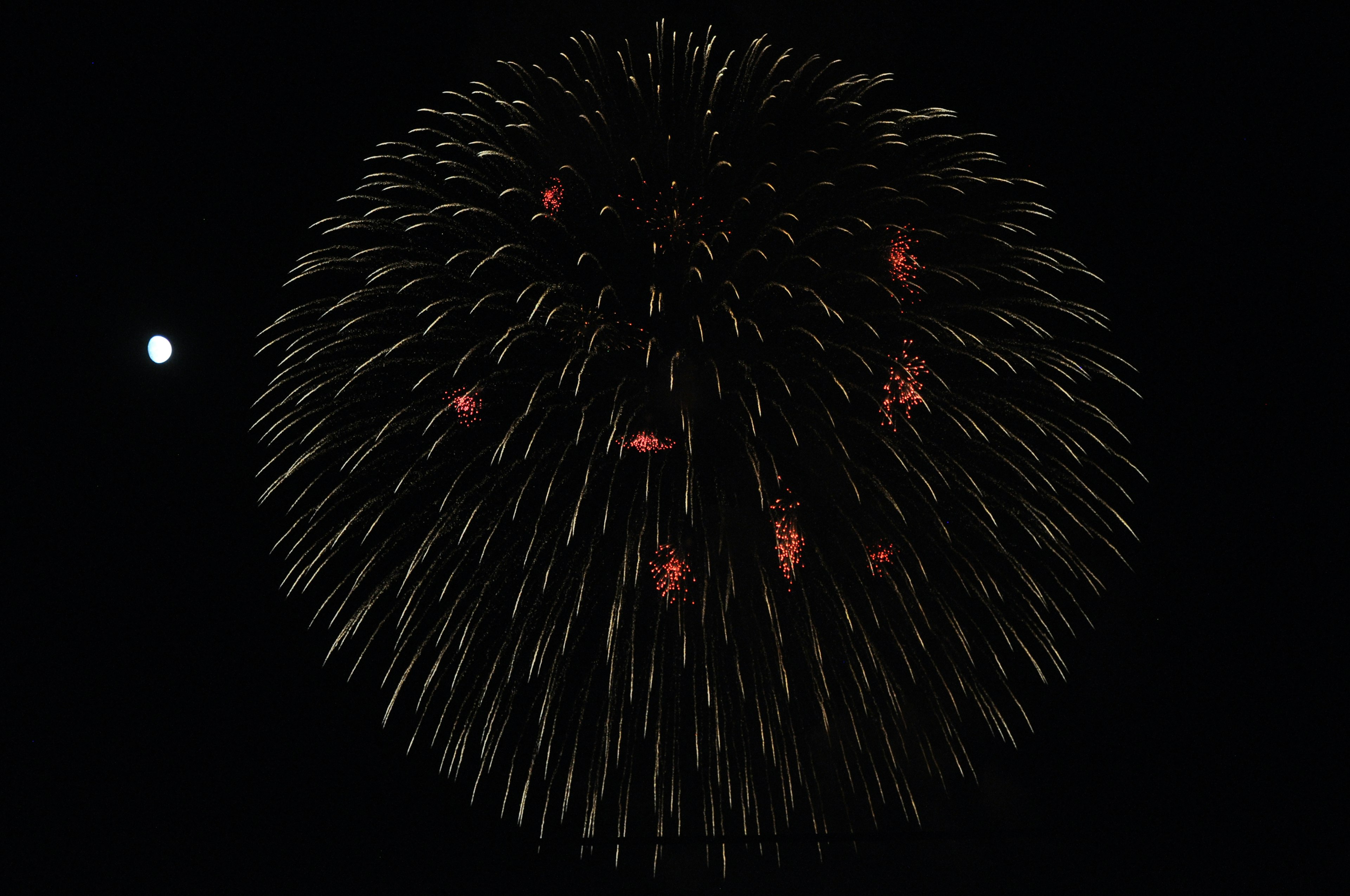 Un grande esplosione di fuochi d'artificio nel cielo notturno con una piccola luna