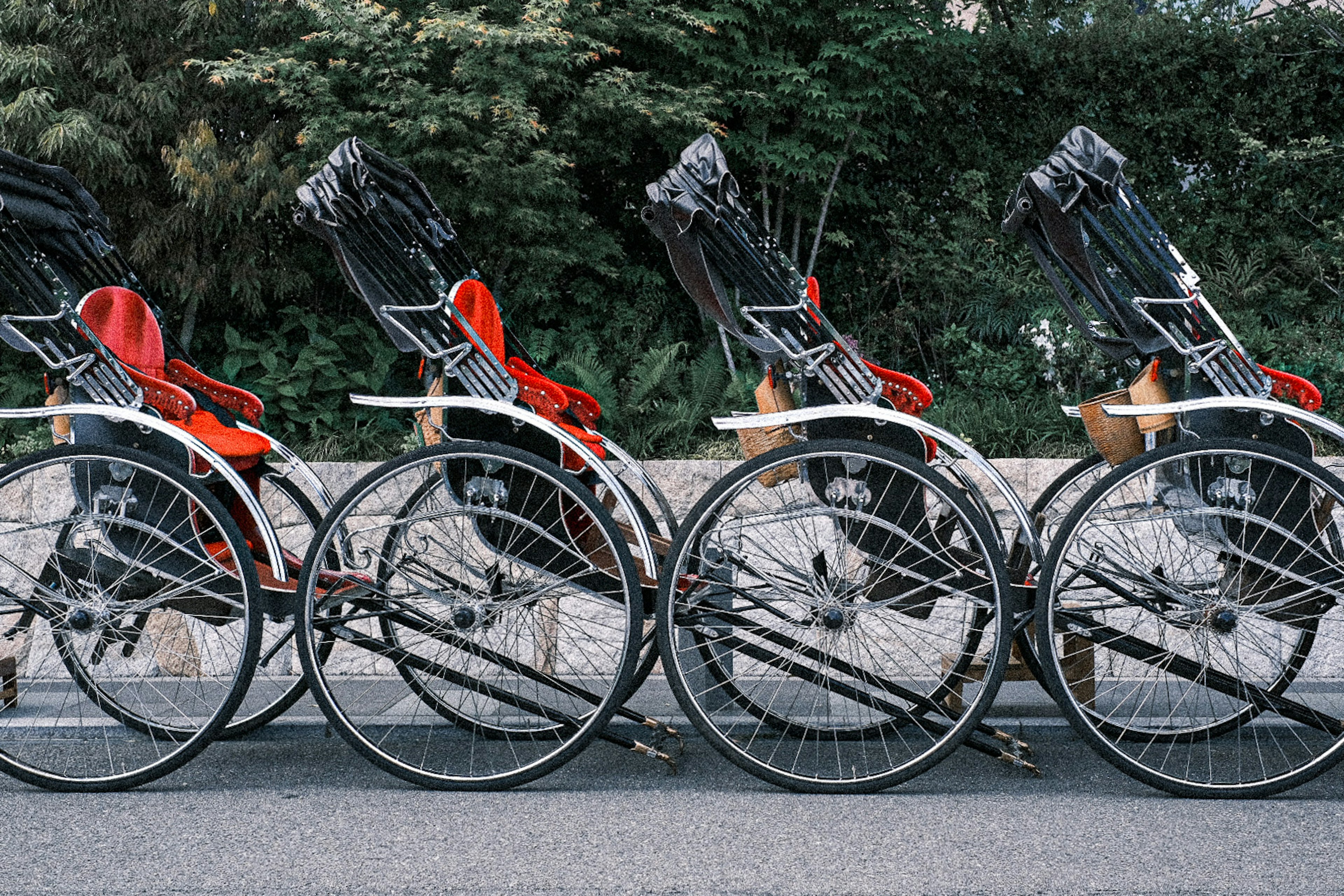 Fila di rickshaw con sedili rossi parcheggiati sulla strada