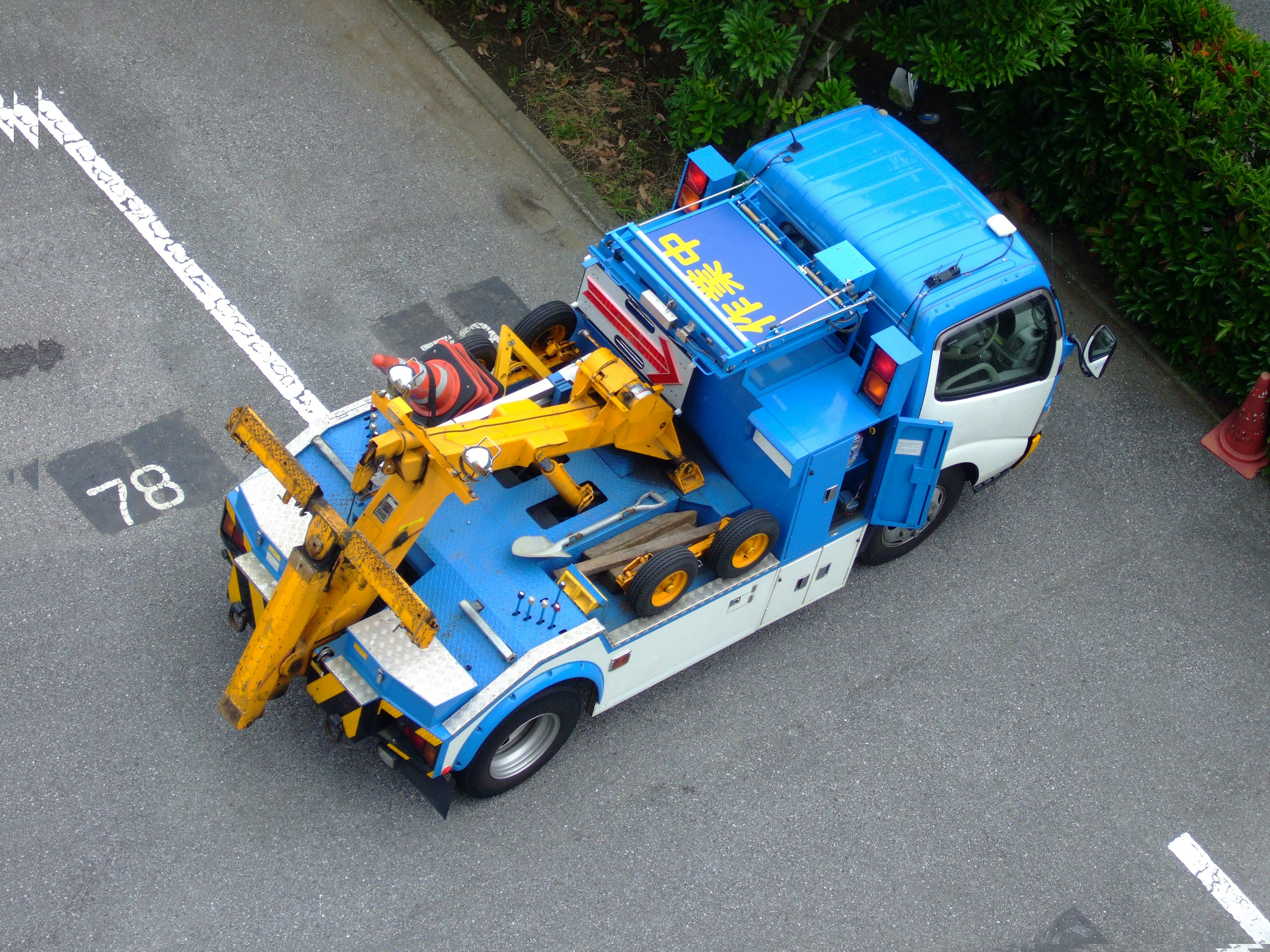 Un camion blu con una gru gialla e vari attrezzi sopra