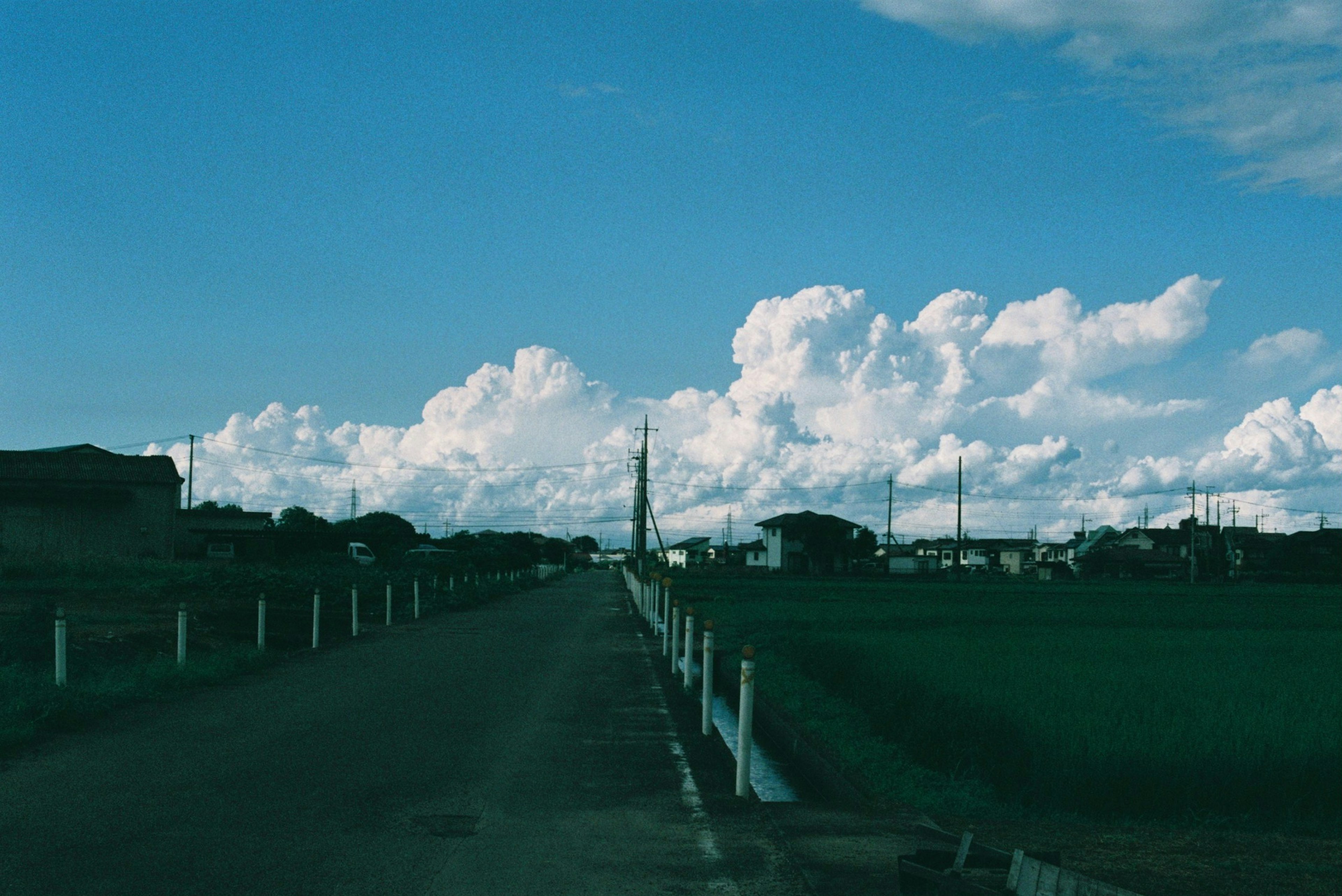 青空の下の田舎道と白い雲が広がる風景