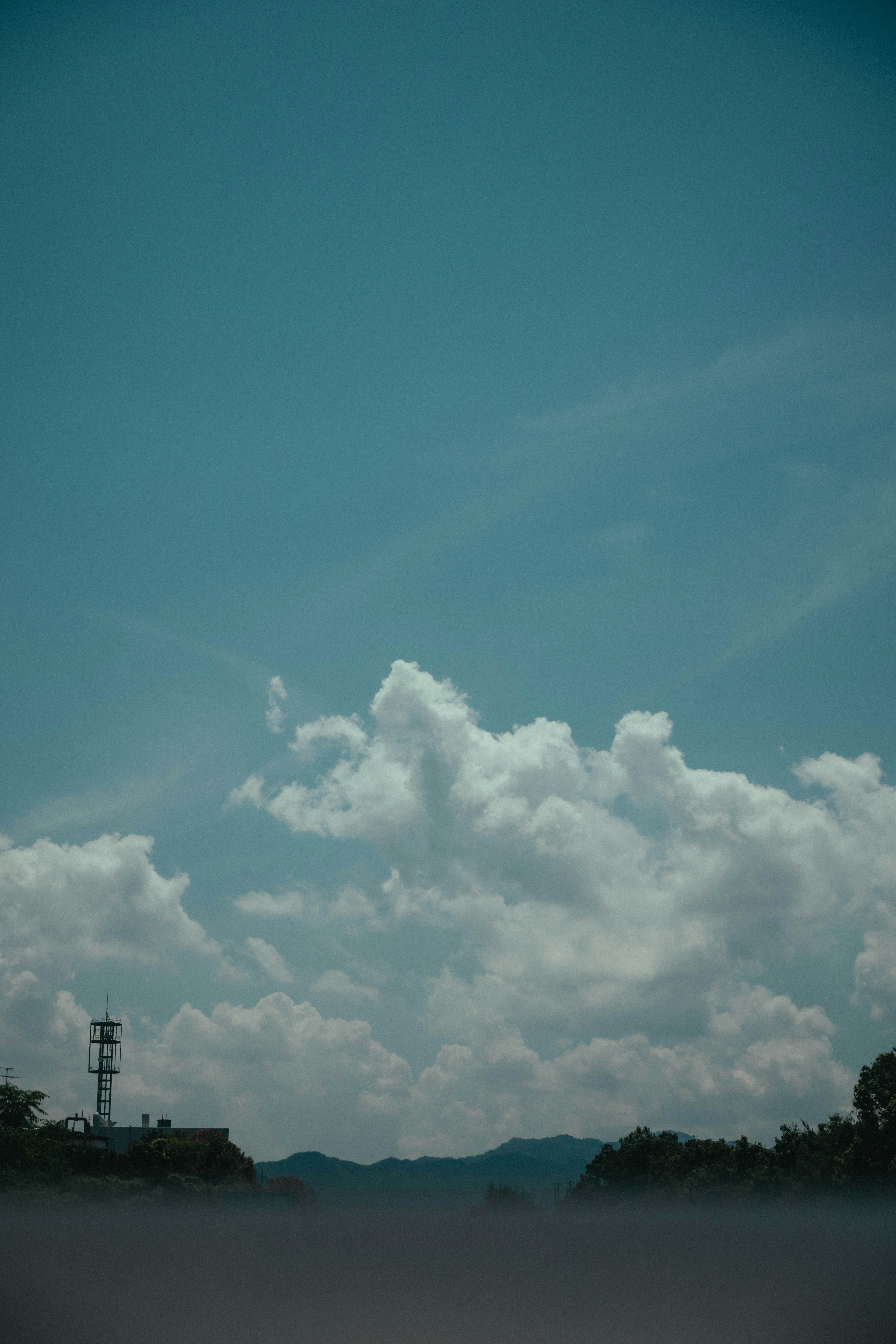 Pemandangan tenang dengan langit biru dan awan putih berbulu