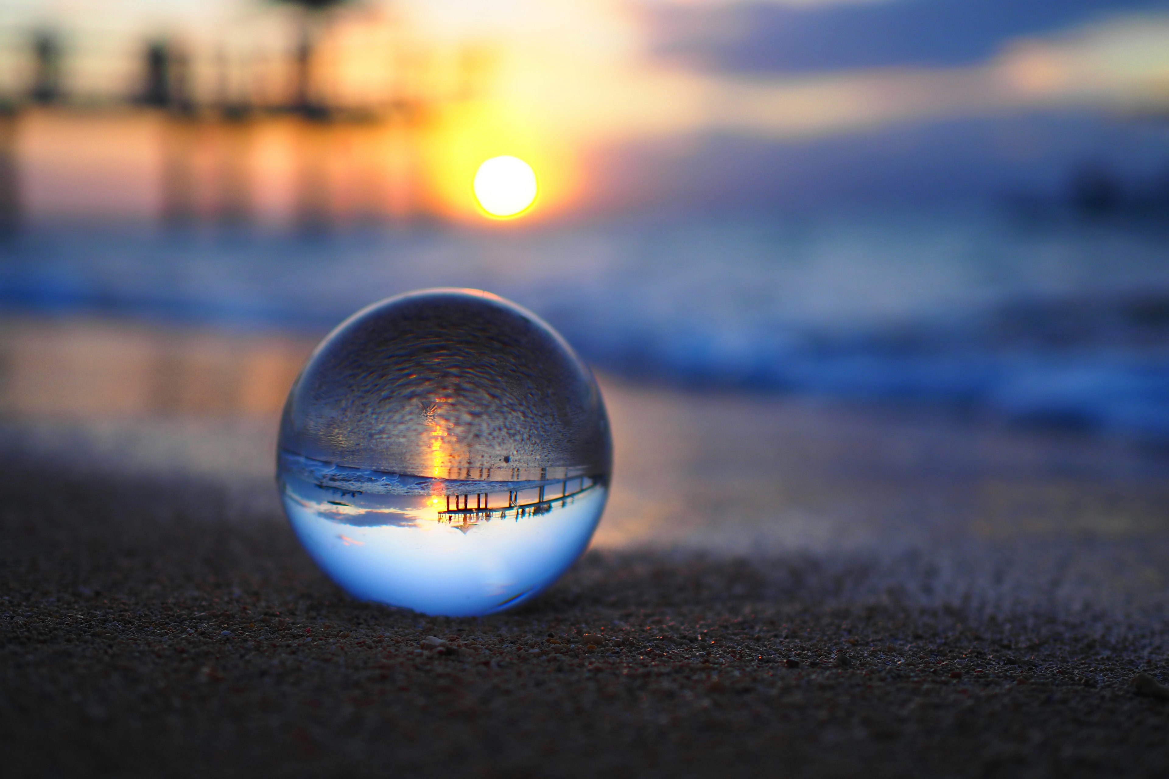 Kristallkugel am Strand, die den Sonnenuntergang reflektiert