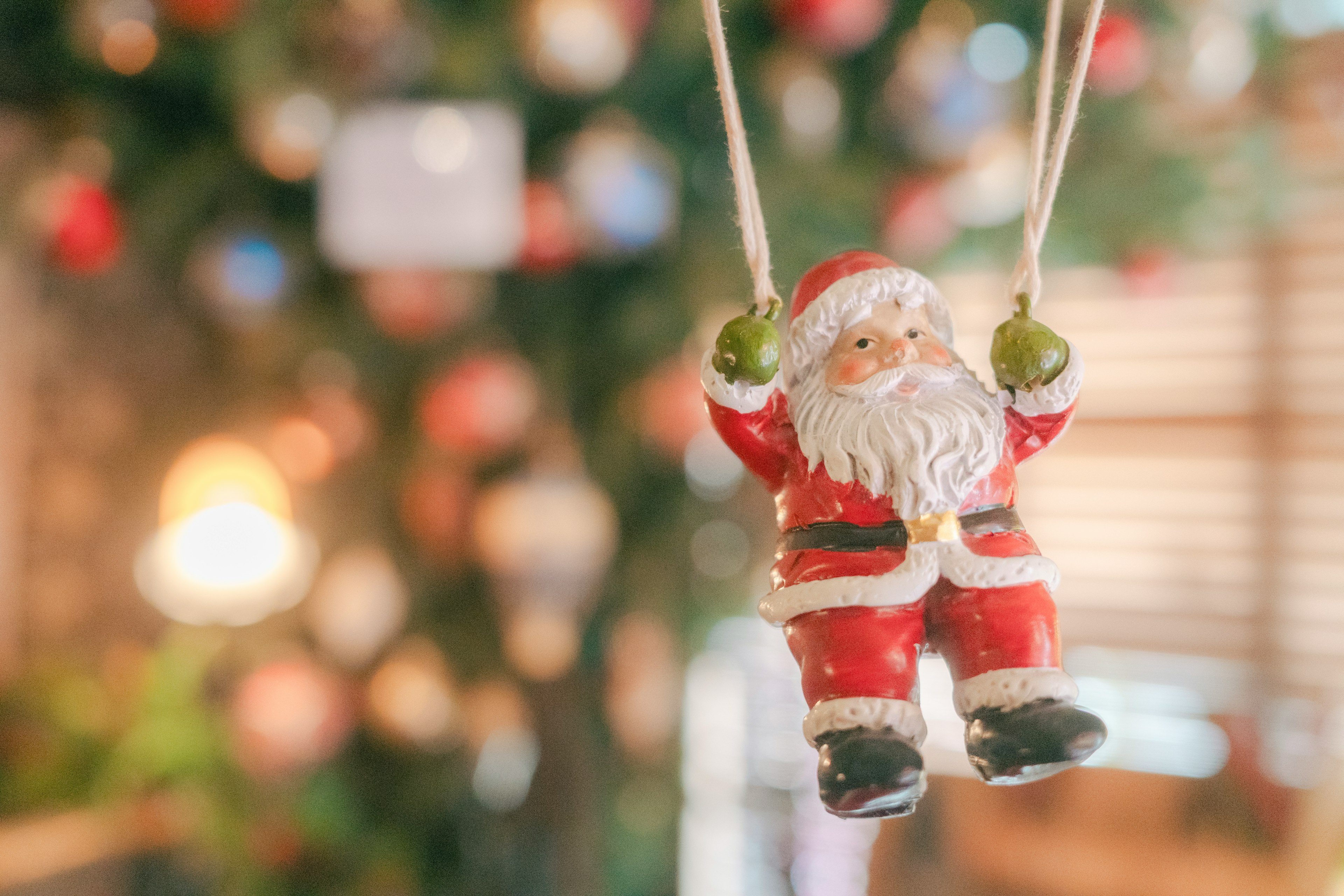 Santa Claus ornament swinging in front of a Christmas tree