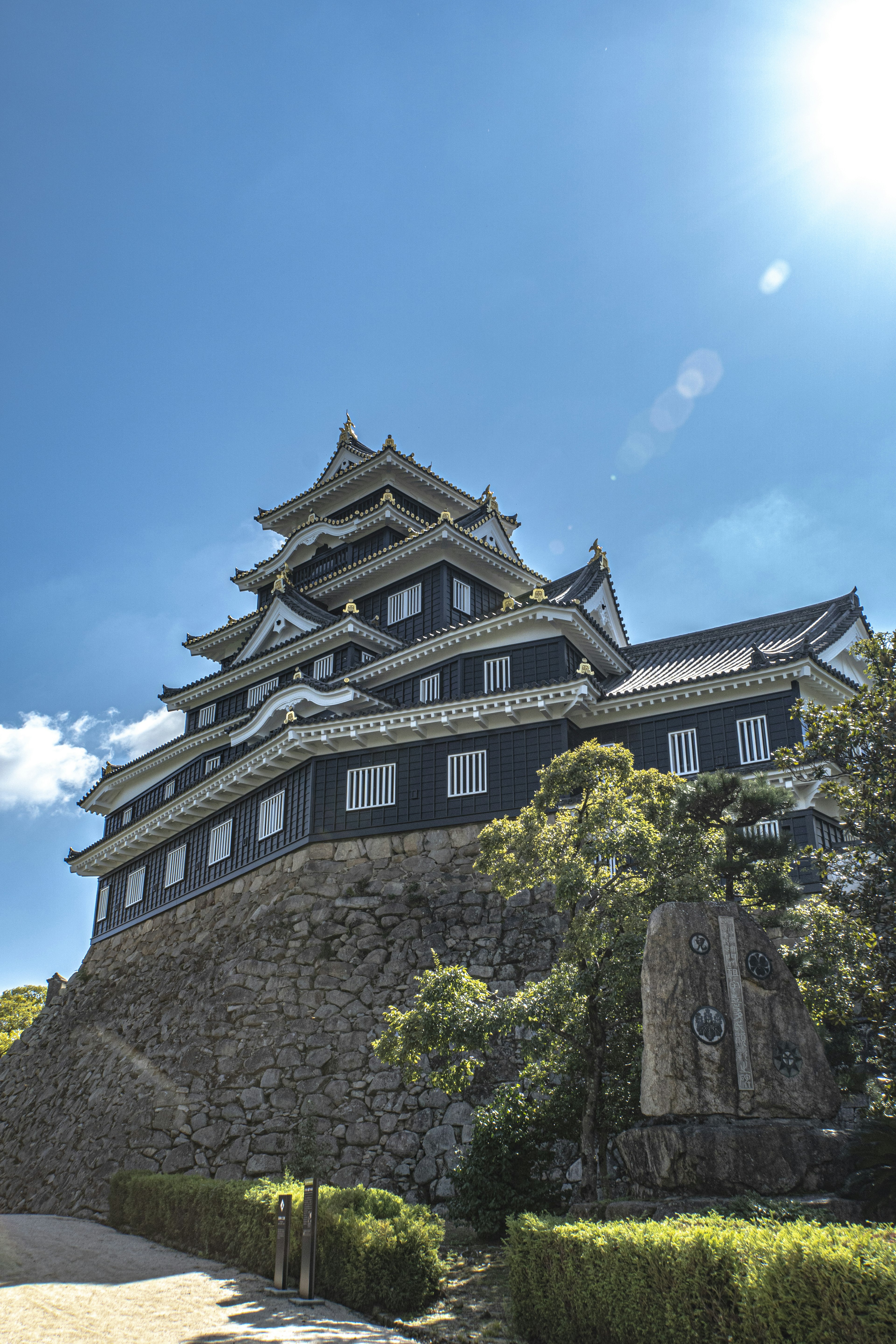 Castillo negro que se eleva bajo un cielo azul con vegetación exuberante