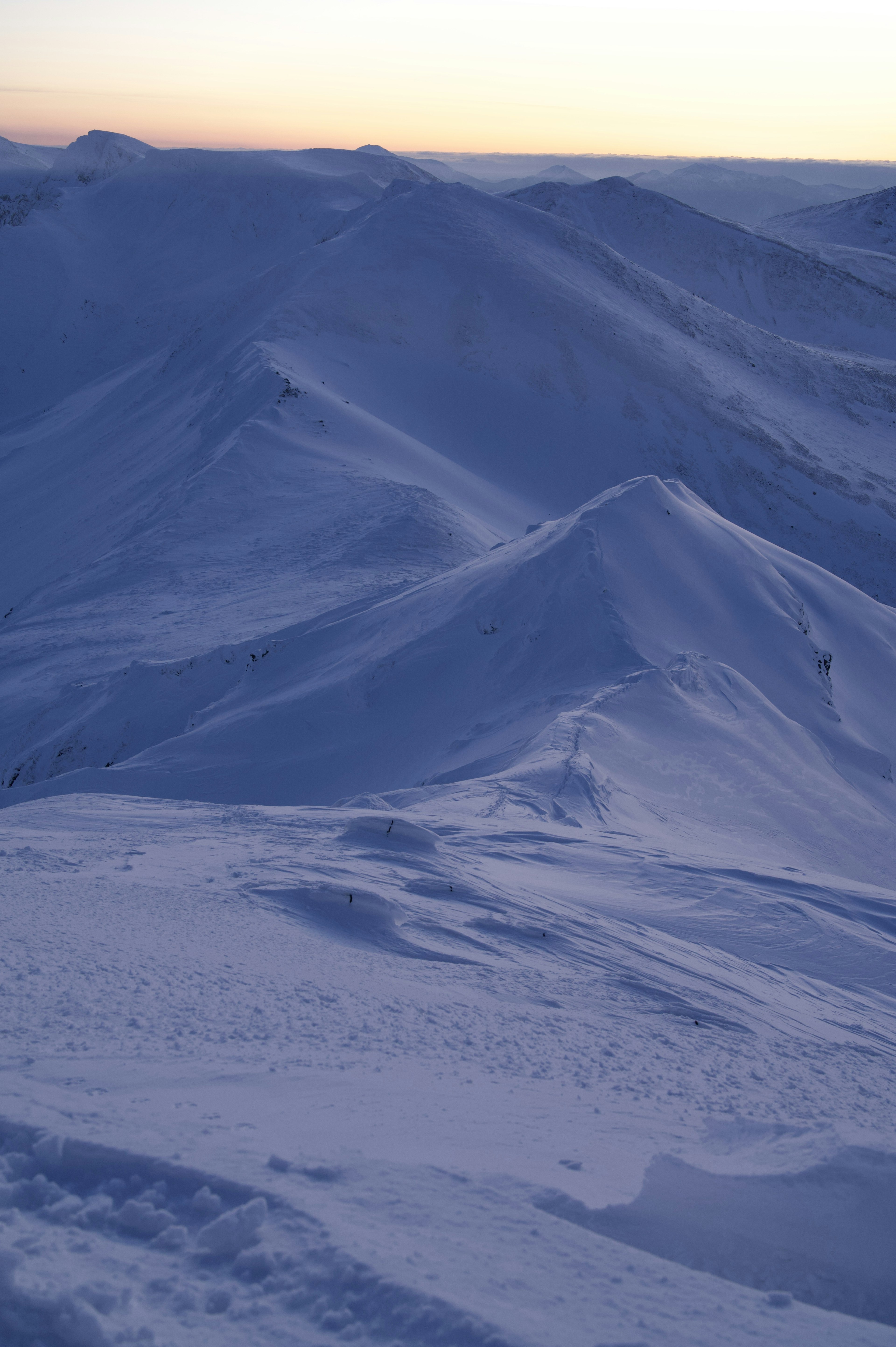 Paisaje montañoso cubierto de nieve con tonos azules al atardecer