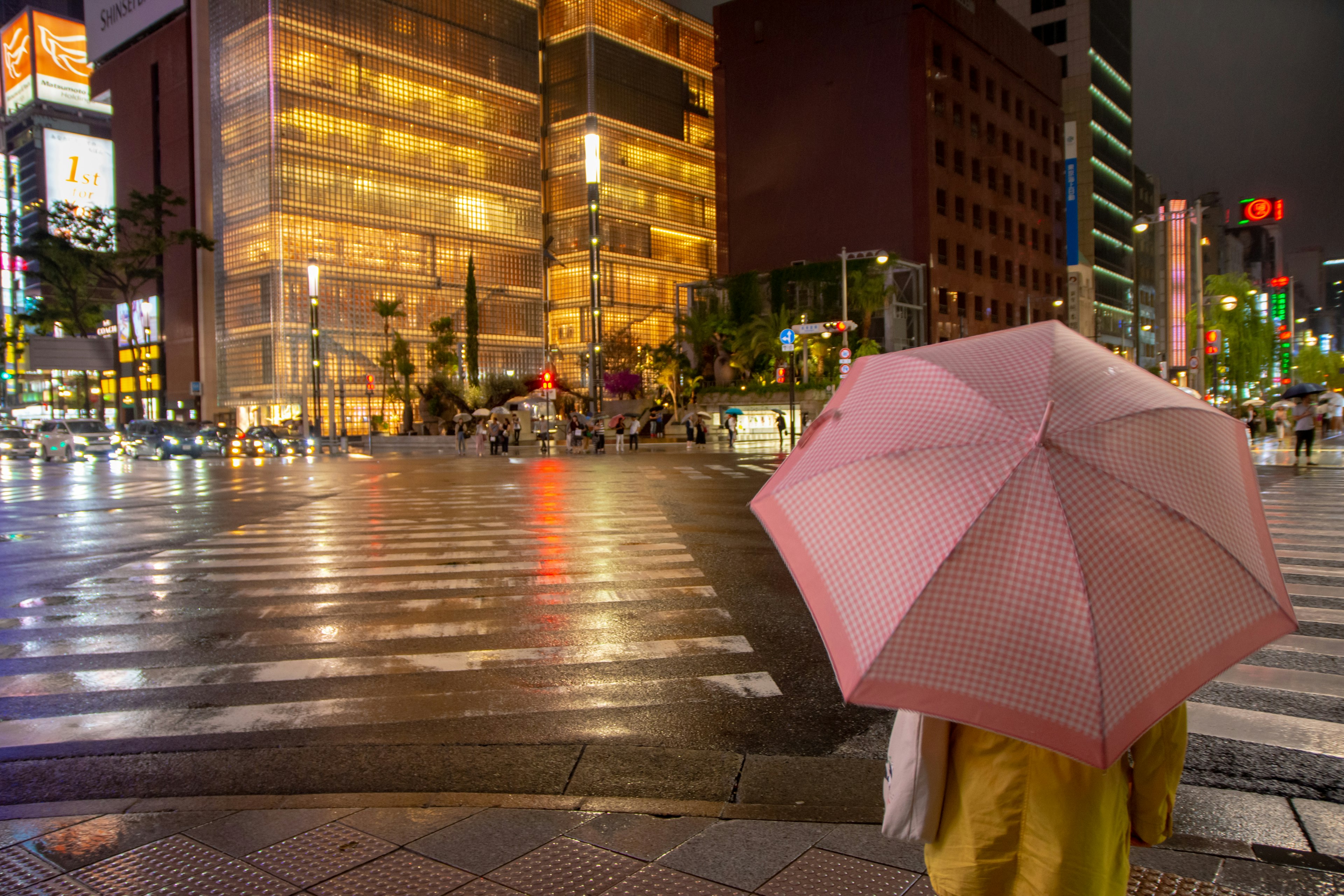 夜の街角でピンクの傘を持つ人