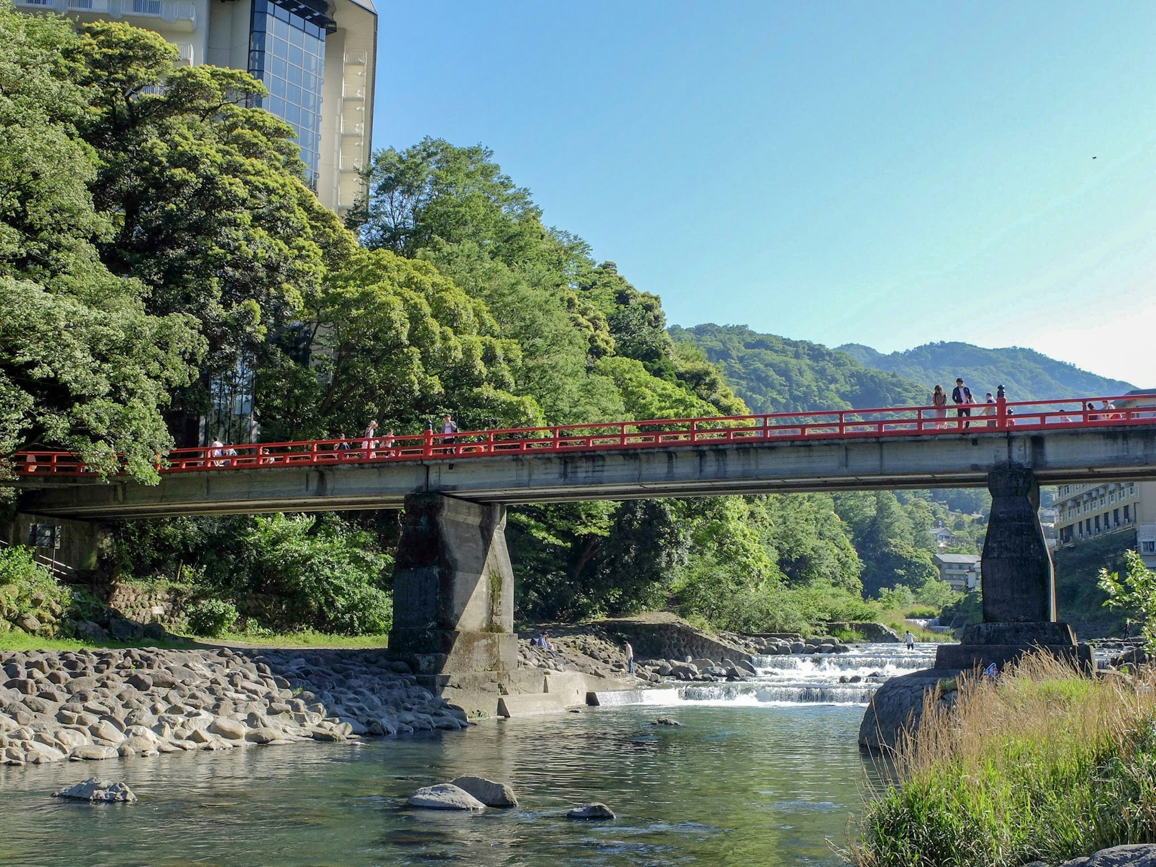 ทัศนียภาพของสะพานแดงเหนือแม่น้ำที่มีความเขียวขจีล้อมรอบ