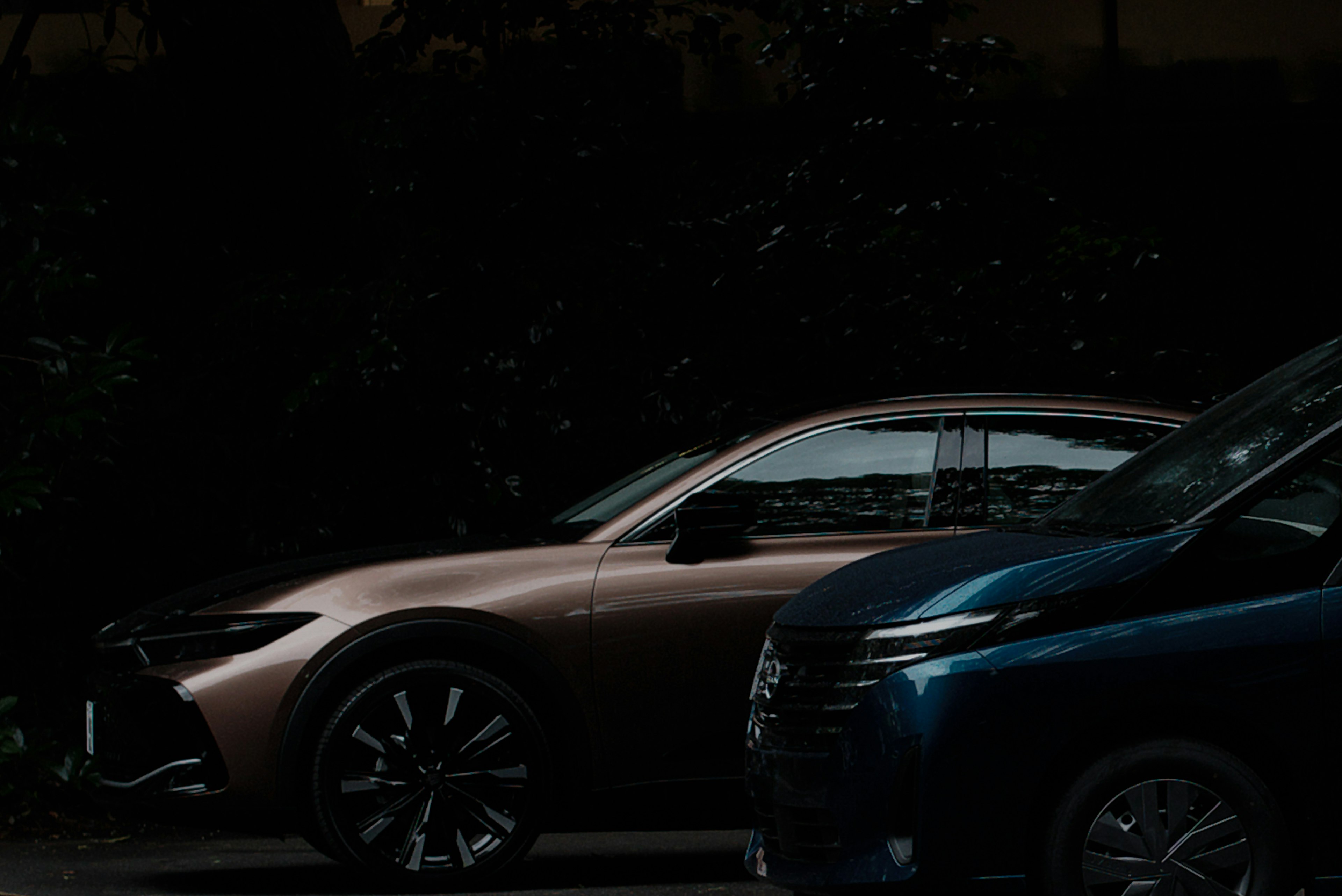 Side view of two cars parked in a dark setting