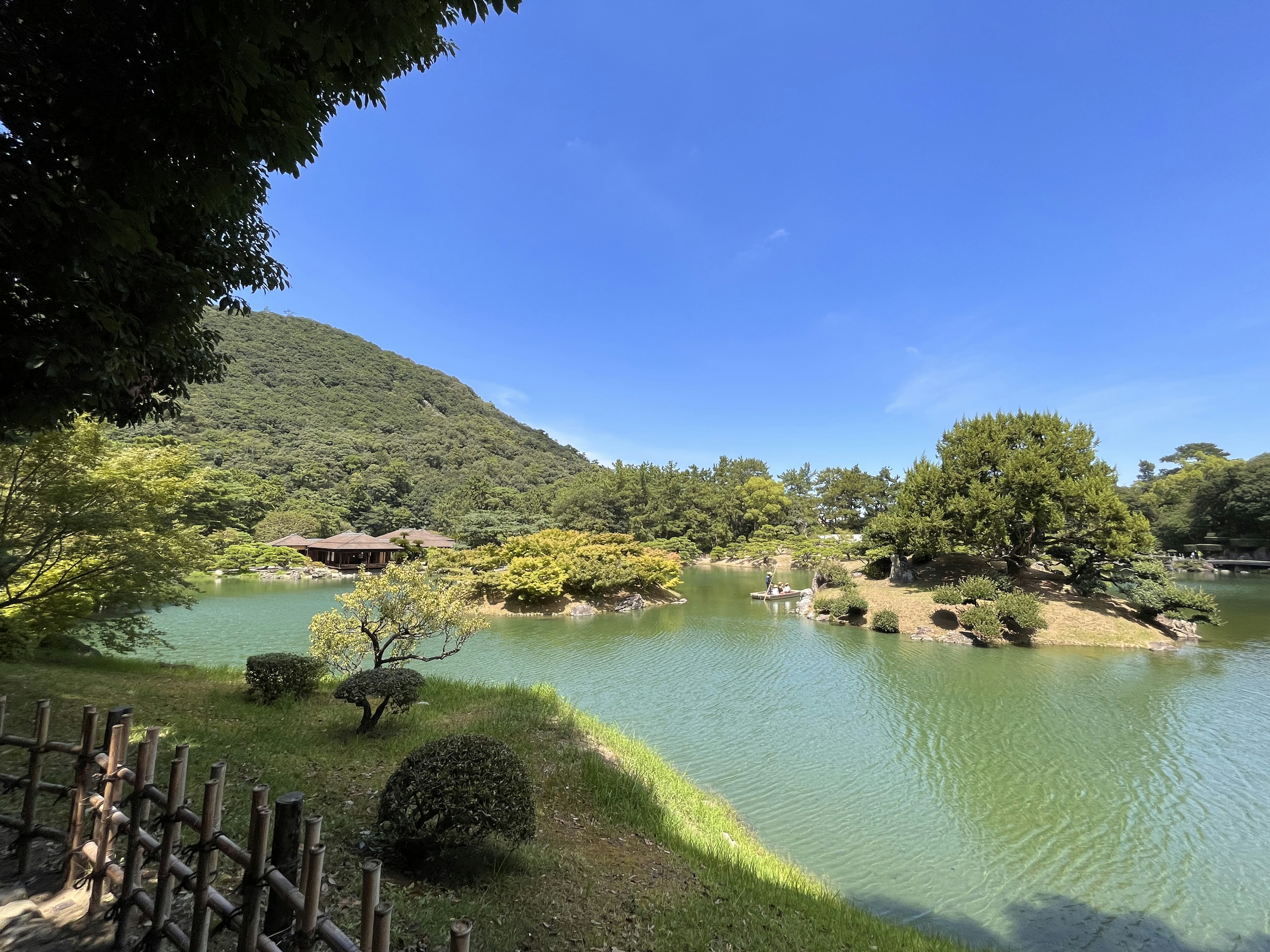 青い空と緑の木々に囲まれた静かな池の風景