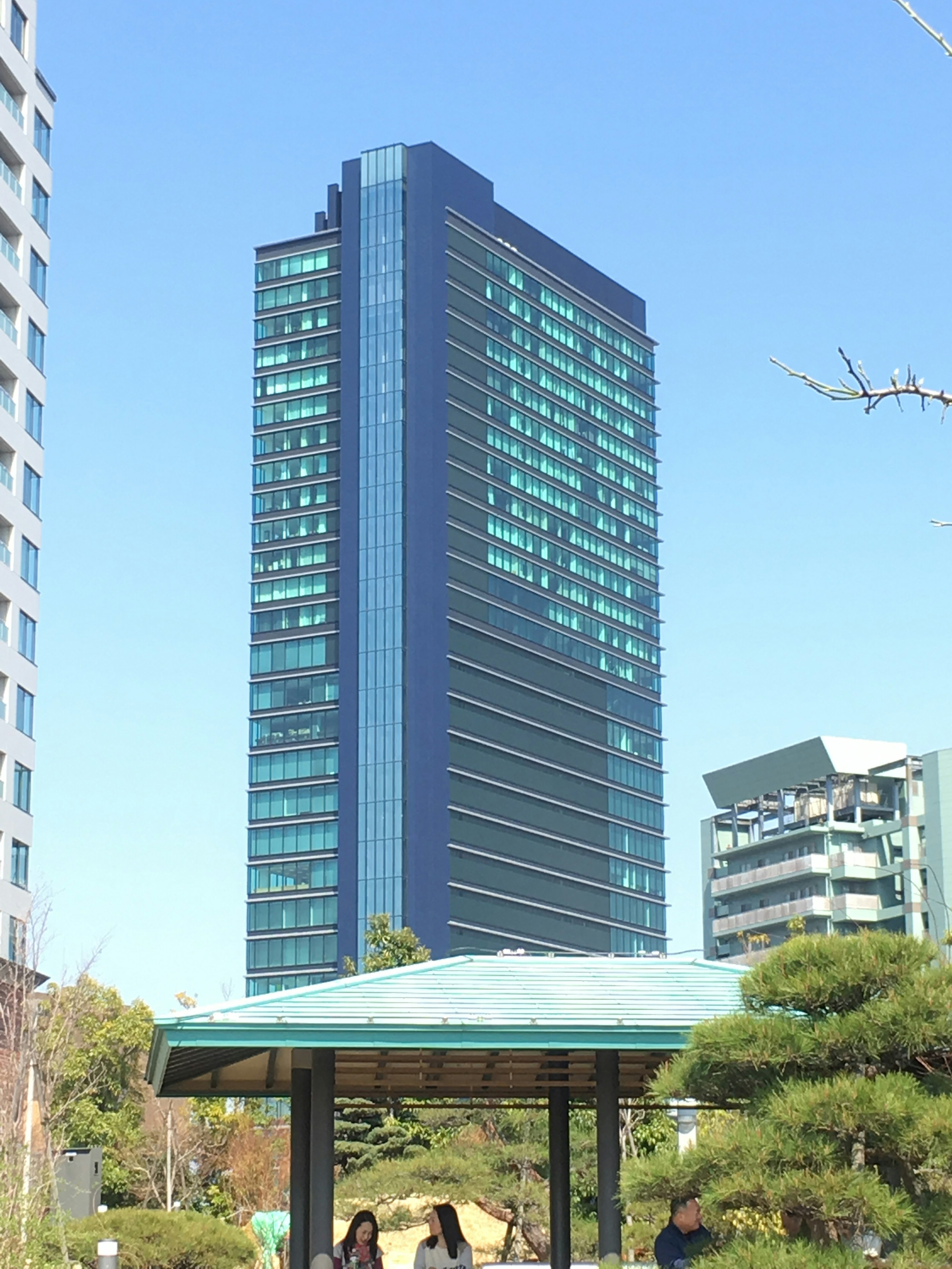 A tall building under a blue sky with a gazebo in the foreground