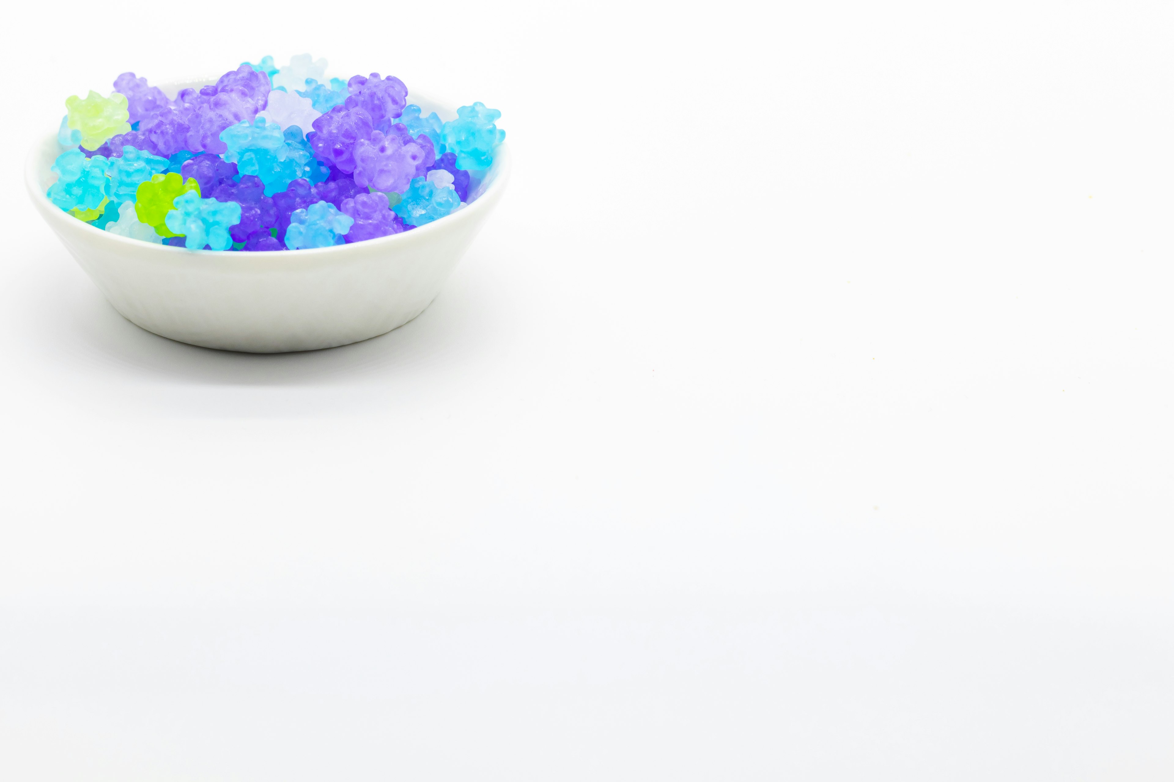 Colorful jelly flowers in a white bowl on a white background