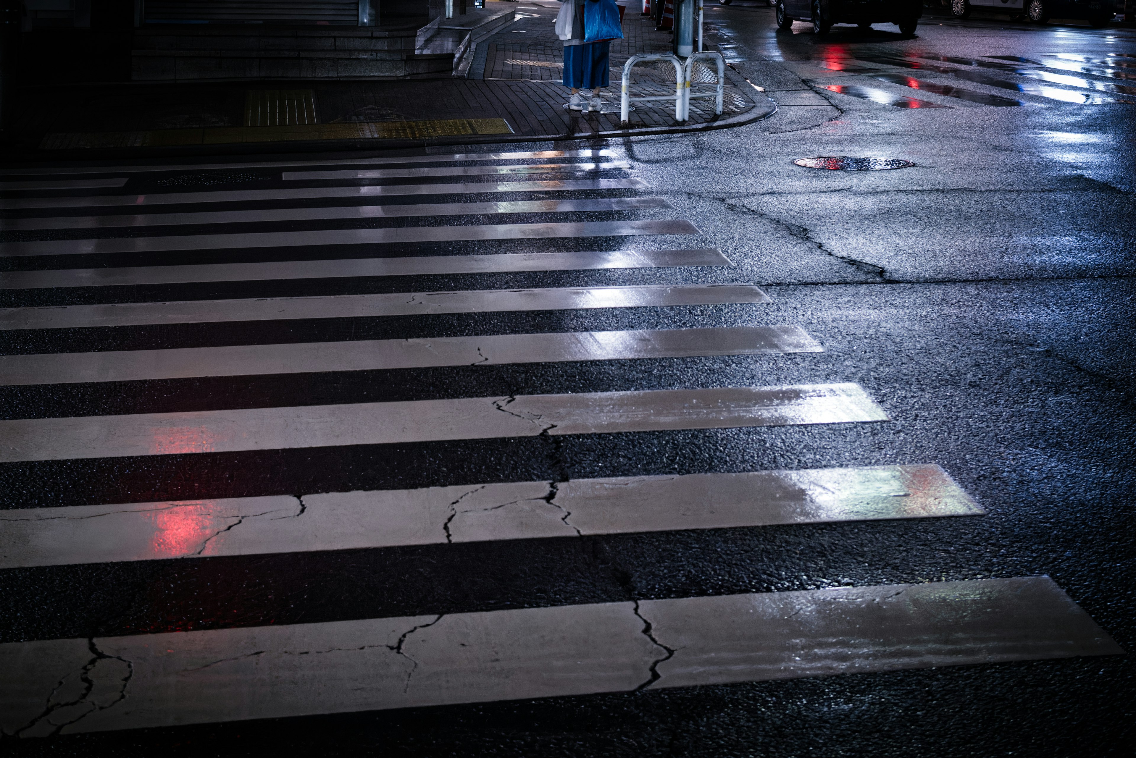 Wet crosswalk with streetlight reflections in a nighttime scene