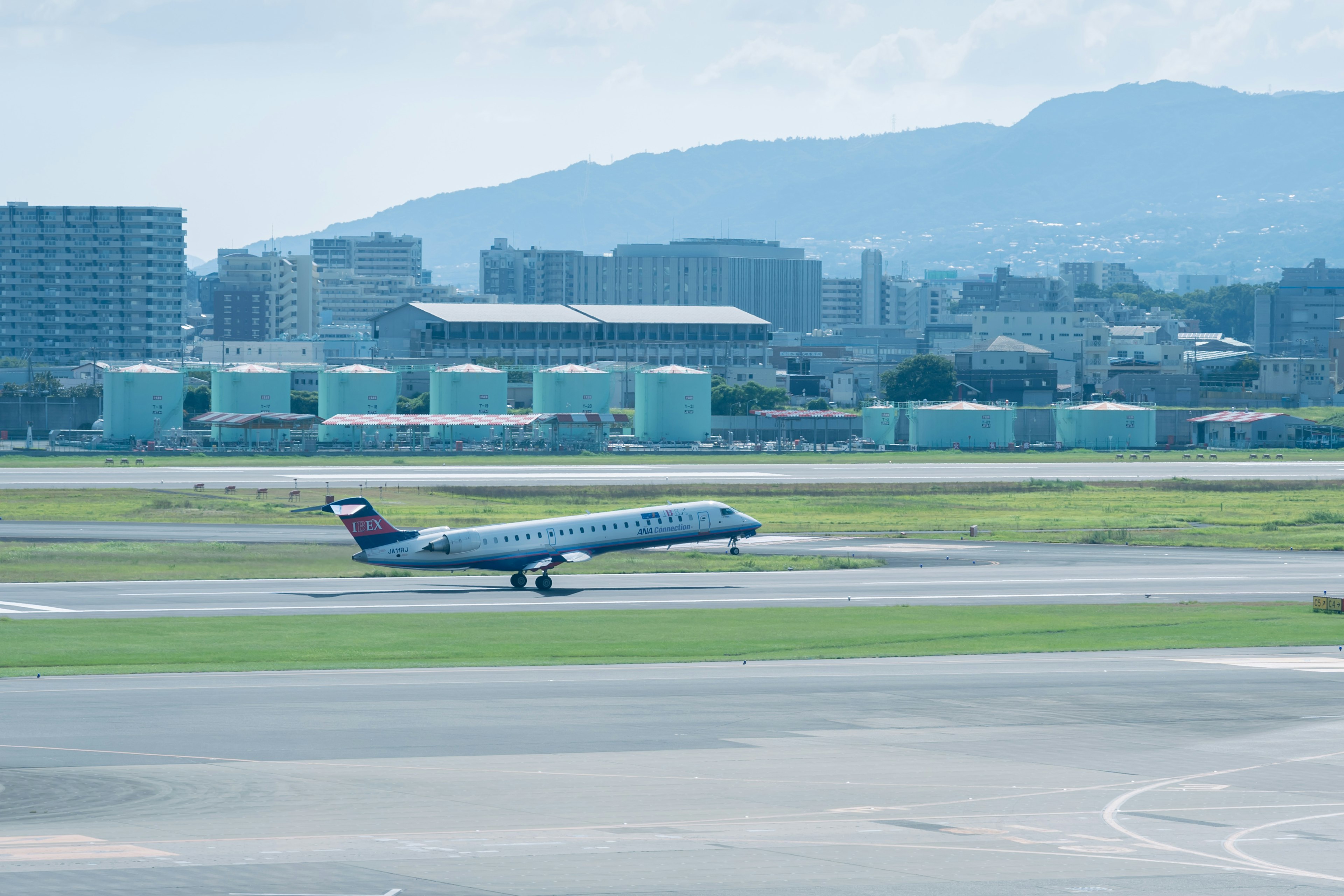 Aereo in fase di rullaggio sulla pista con skyline urbano sullo sfondo