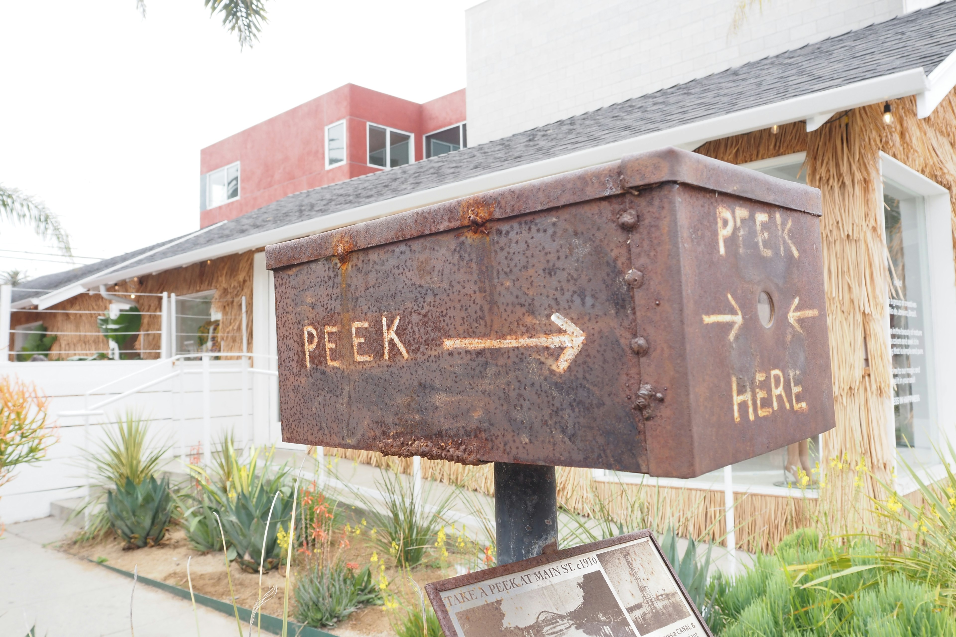 Rusty mailbox with arrows and the text 'PEEK HERE'