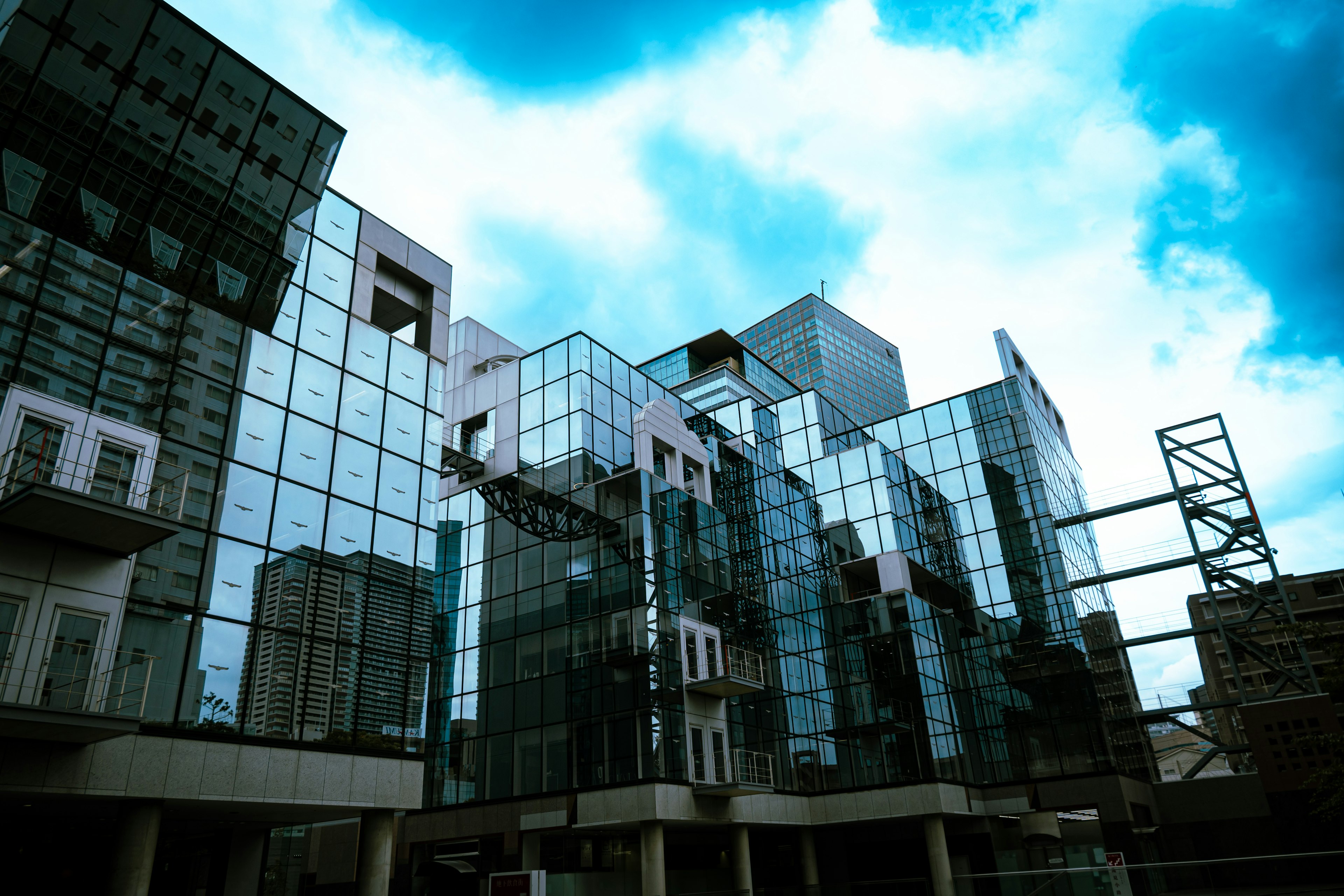 Modern glass buildings reflecting blue sky with clouds