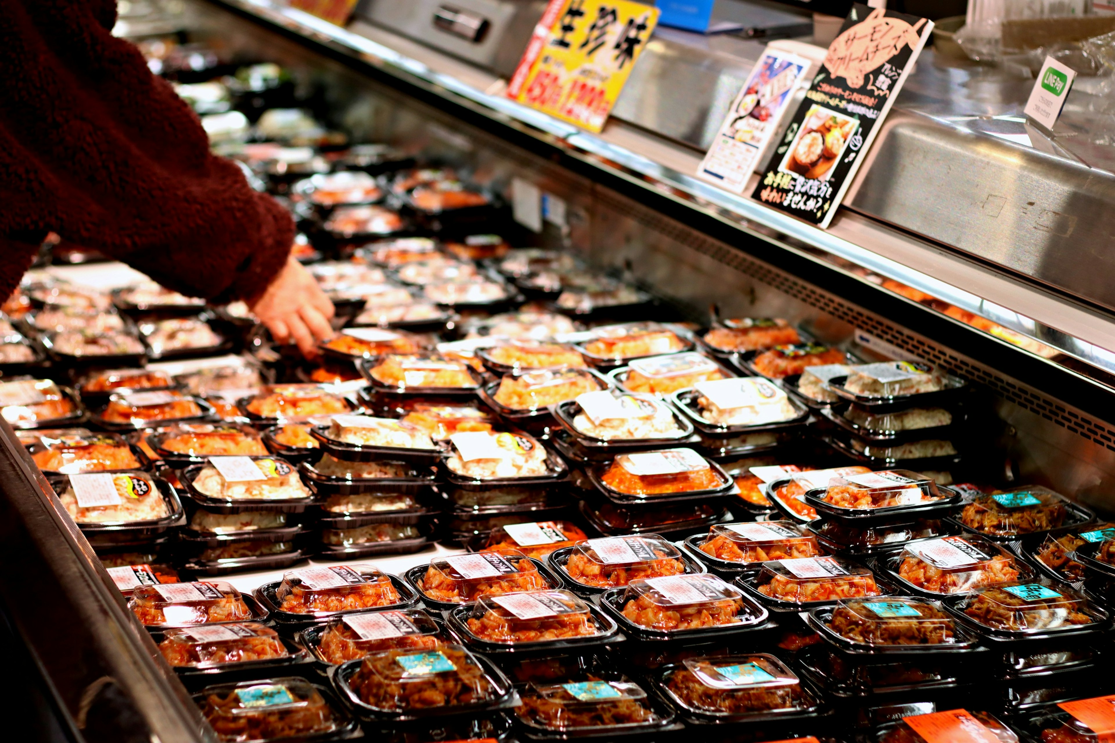 Person selecting food packages from a display of prepared meals