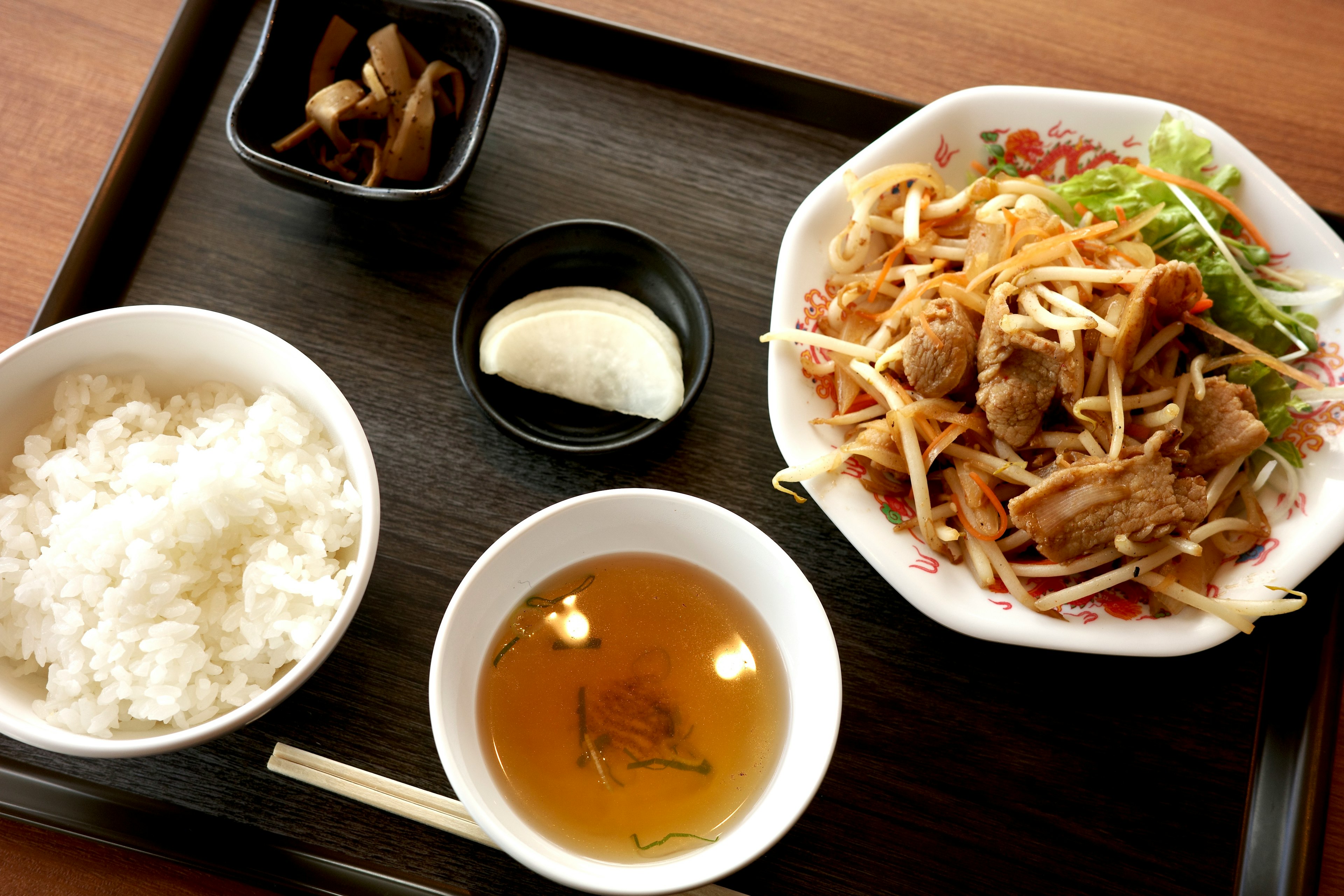 Japanese meal set featuring white rice, chicken salad, soup, and pickles