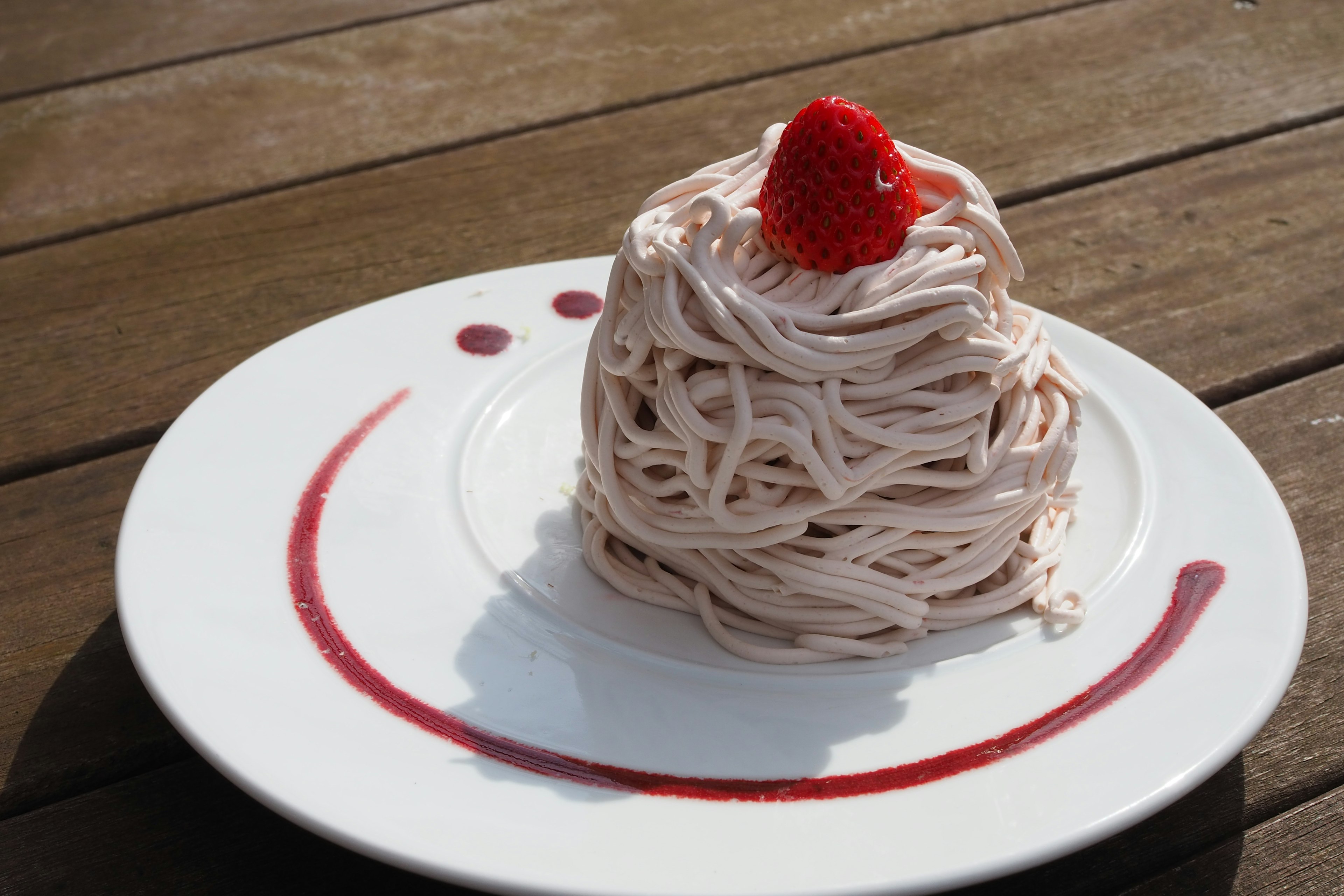 Pastel Mont Blanc decorado con una fresa servido en un plato blanco