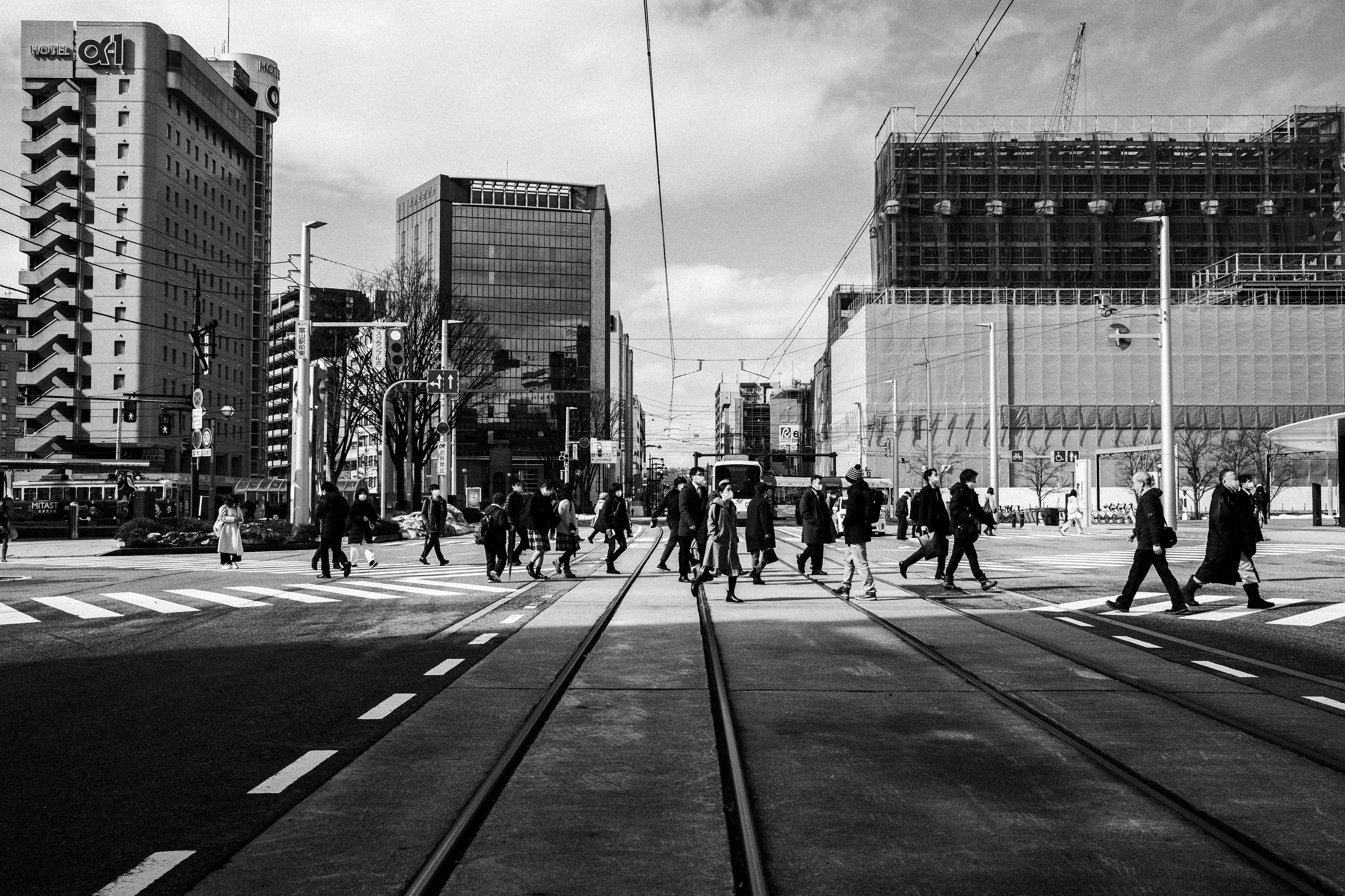 都市の交差点で歩行者が横断しているモノクロの風景