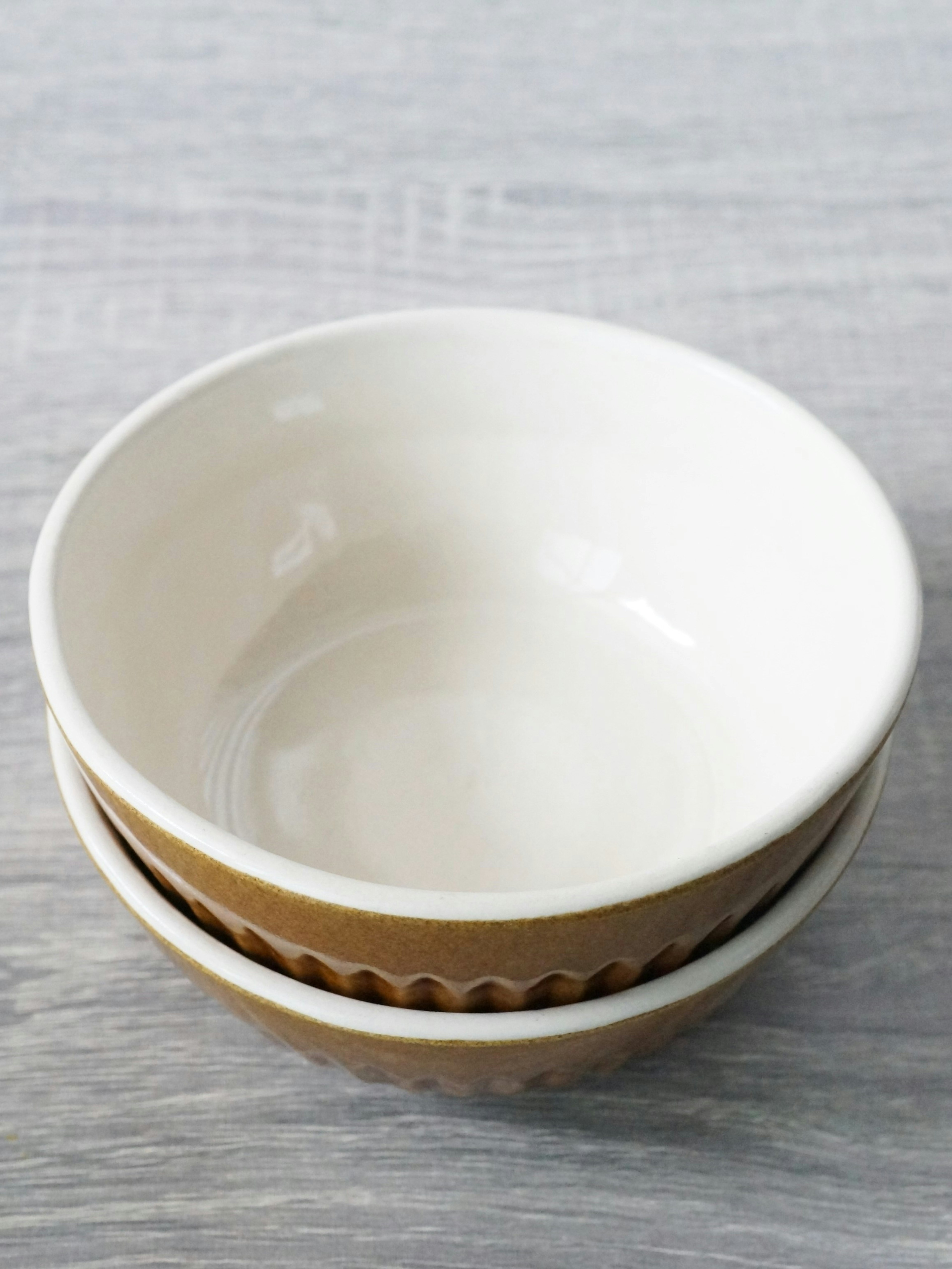 A stack of a white bowl and a brown bowl with a textured edge