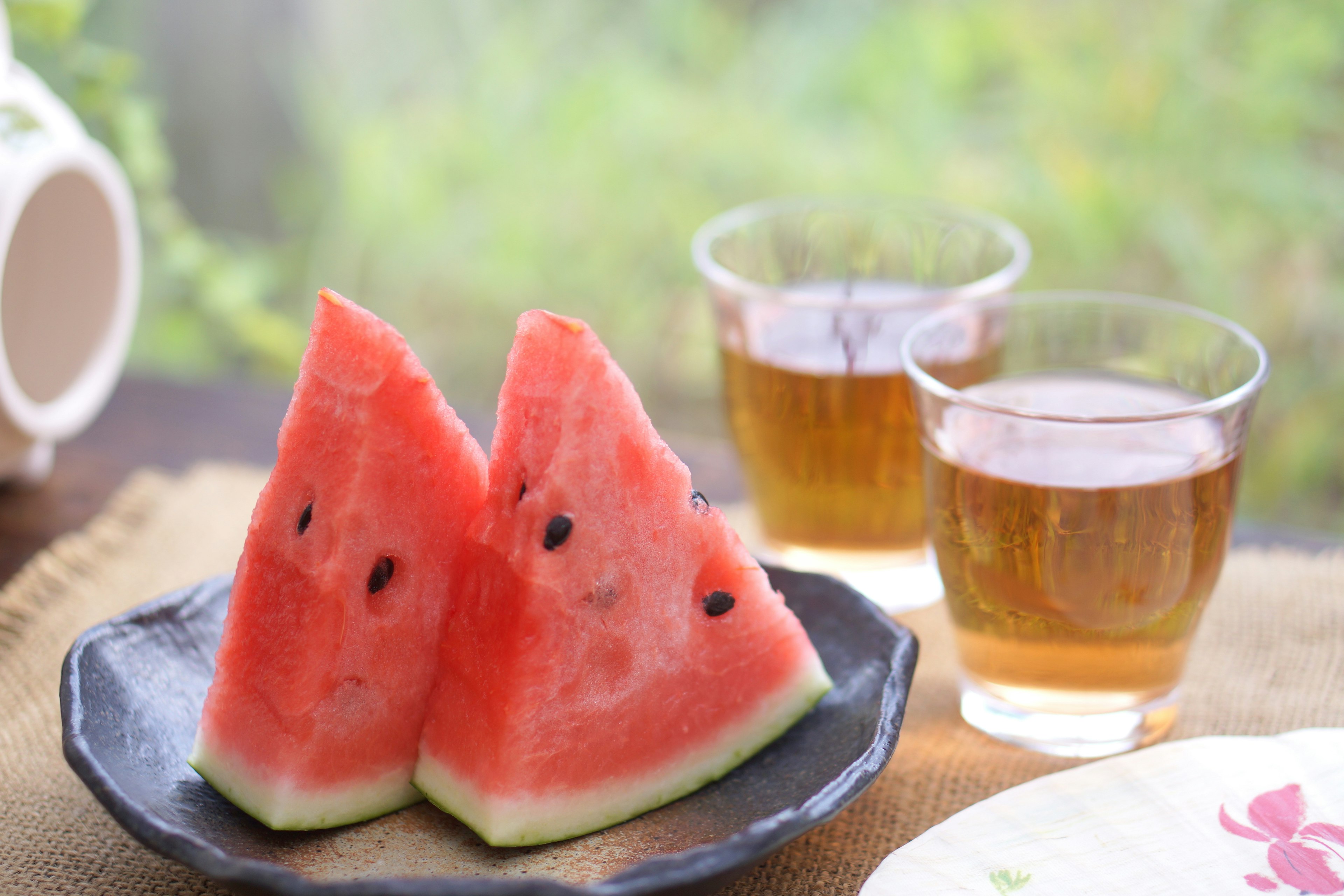 Slices of watermelon and glasses of tea on a table setting