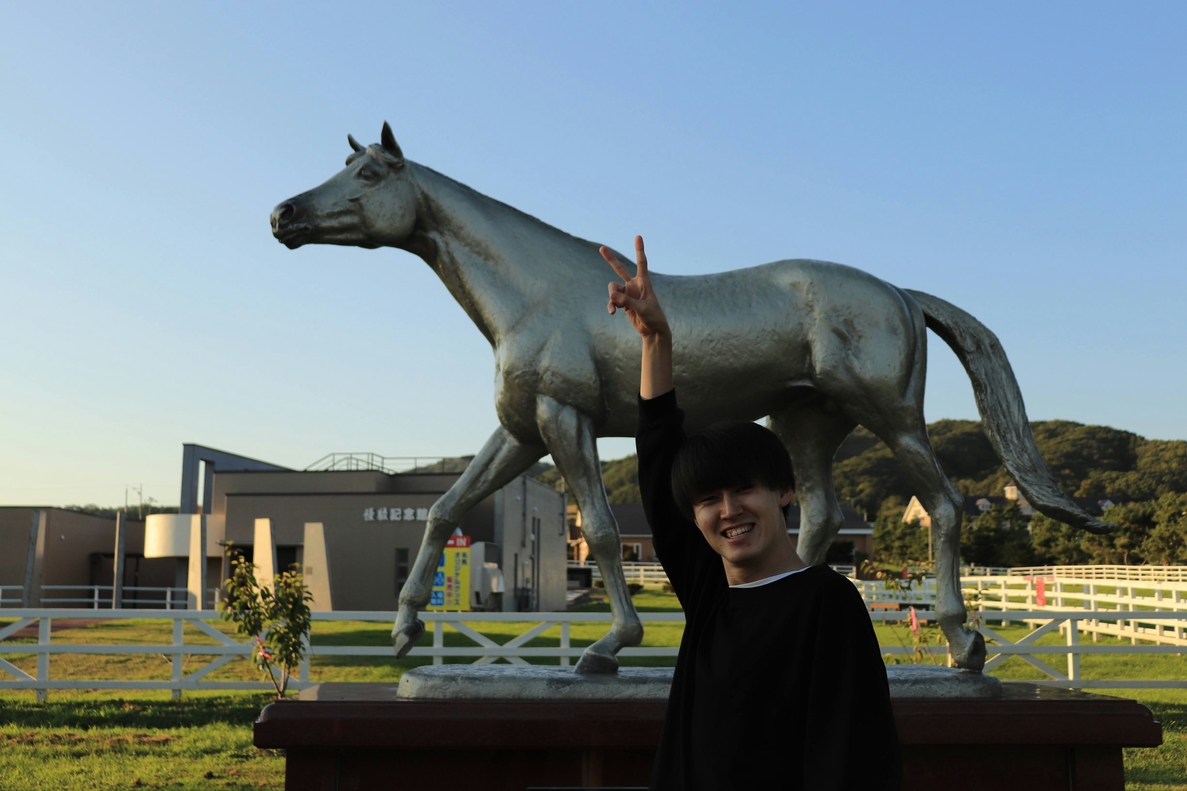 Persona posando frente a una estatua de caballo