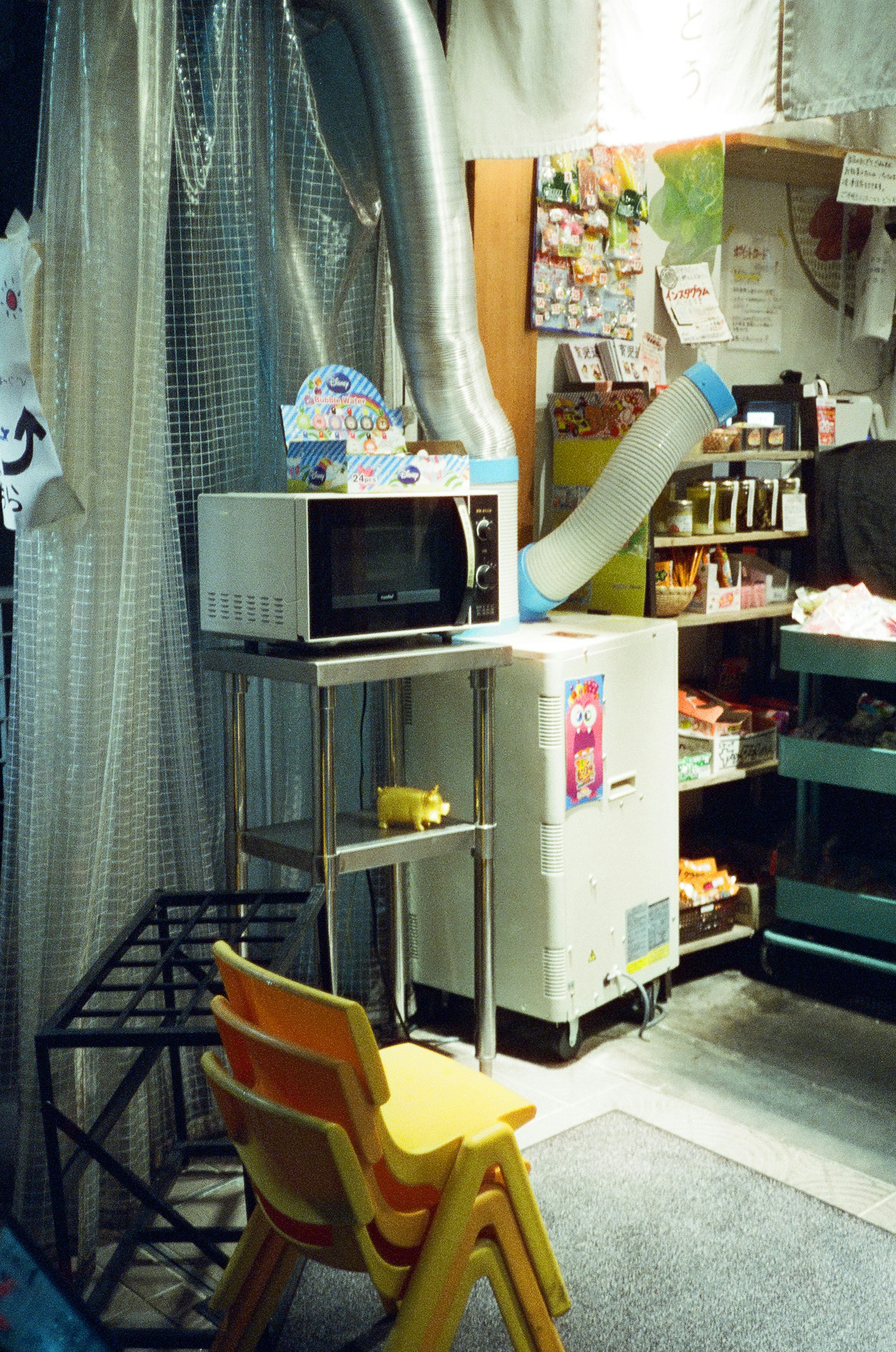 A small kitchen area featuring a microwave and refrigerator yellow chairs and various shelves